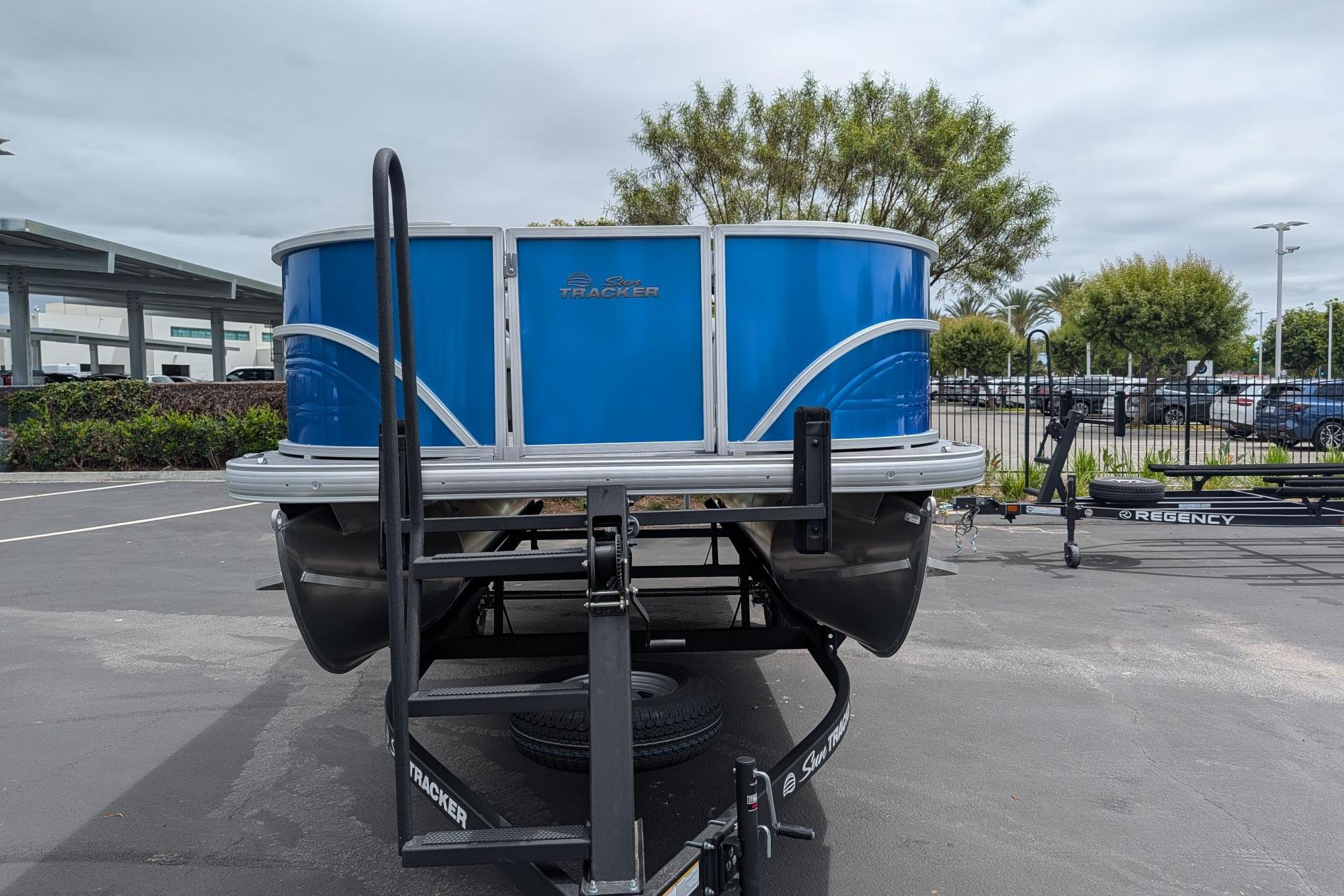2026 Sun Tracker Party Barge 18 DLX pontoon boat on trailer, parked outdoors.