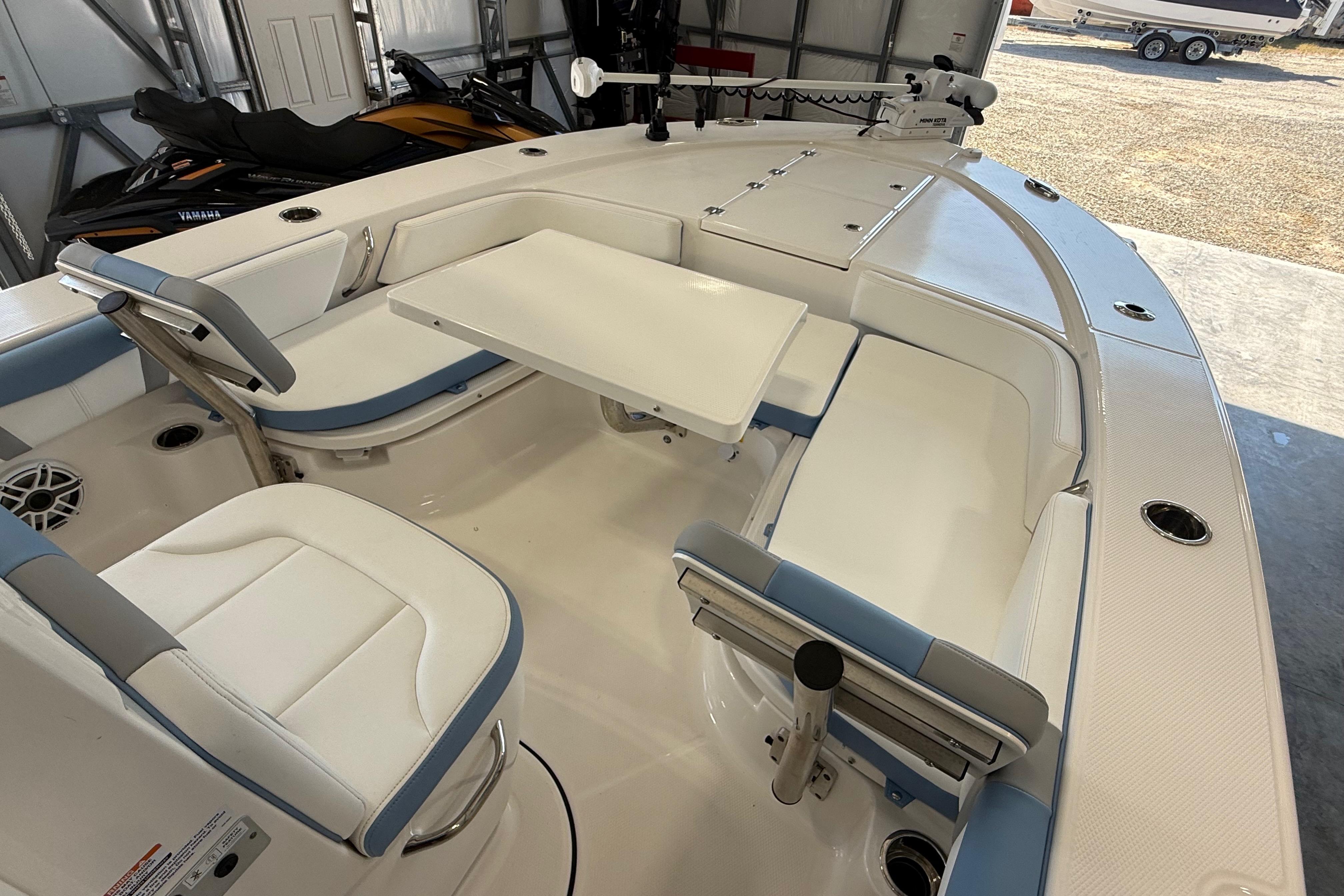 2026 Robalo 246 Cayman boat interior with seating and table in a garage setting.