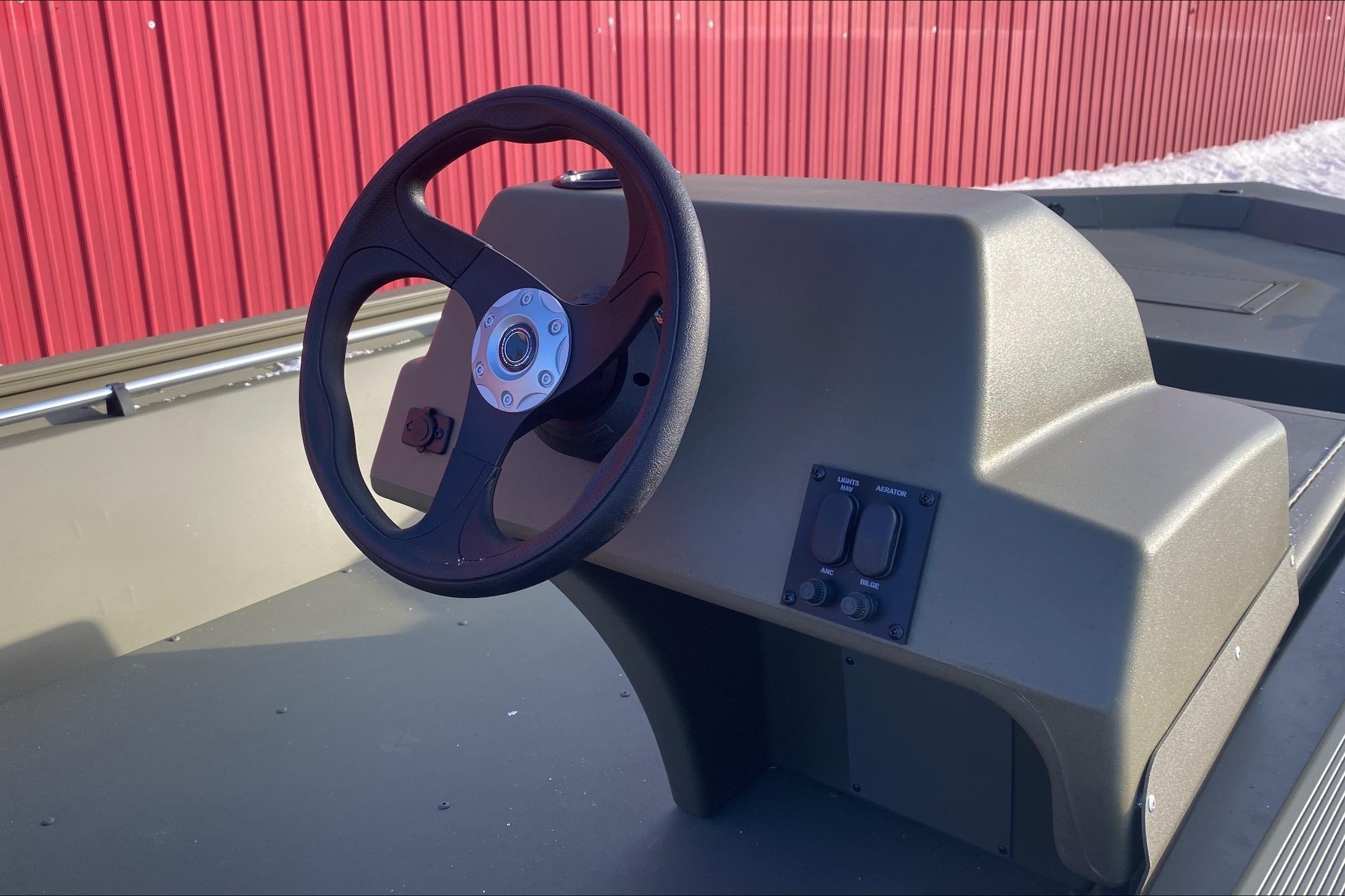 Steering console of 2026 Tracker Grizzly 1648 SC boat with red background.