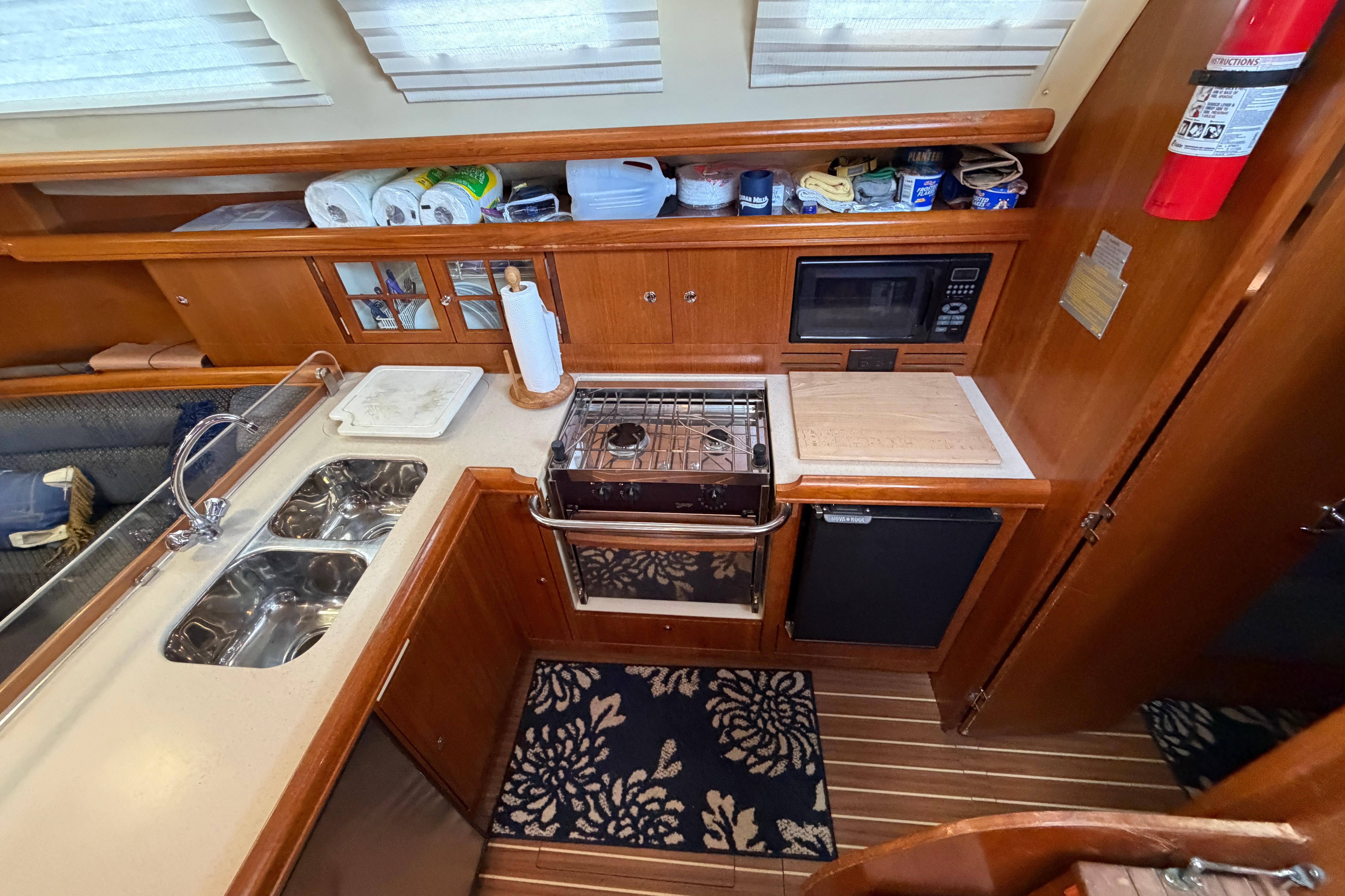 Compact kitchen in a 2005 Hunter 38 yacht with stove, sink, and microwave.