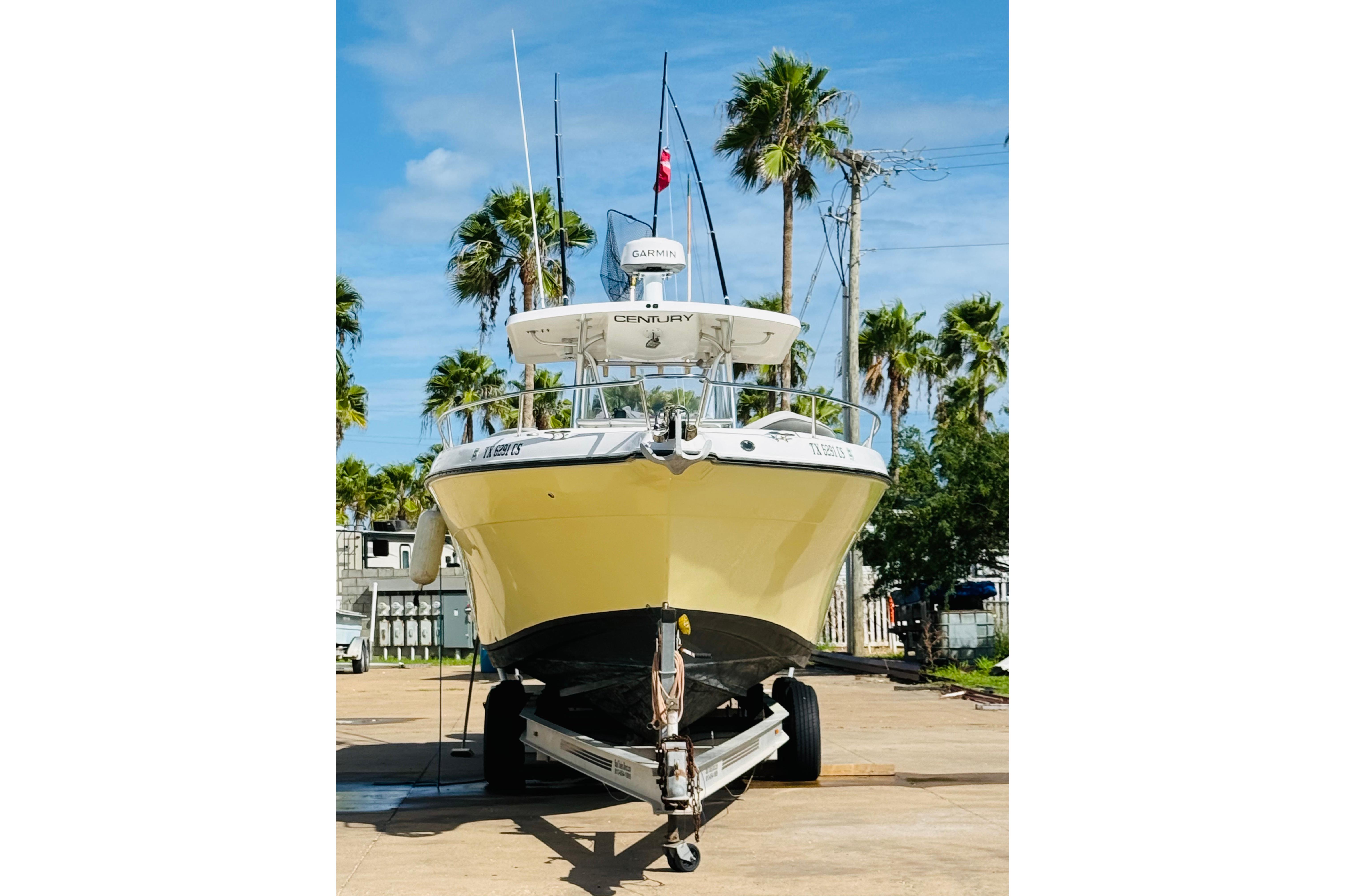 2005 Century 3200 Center Console boat on trailer, surrounded by palm trees.