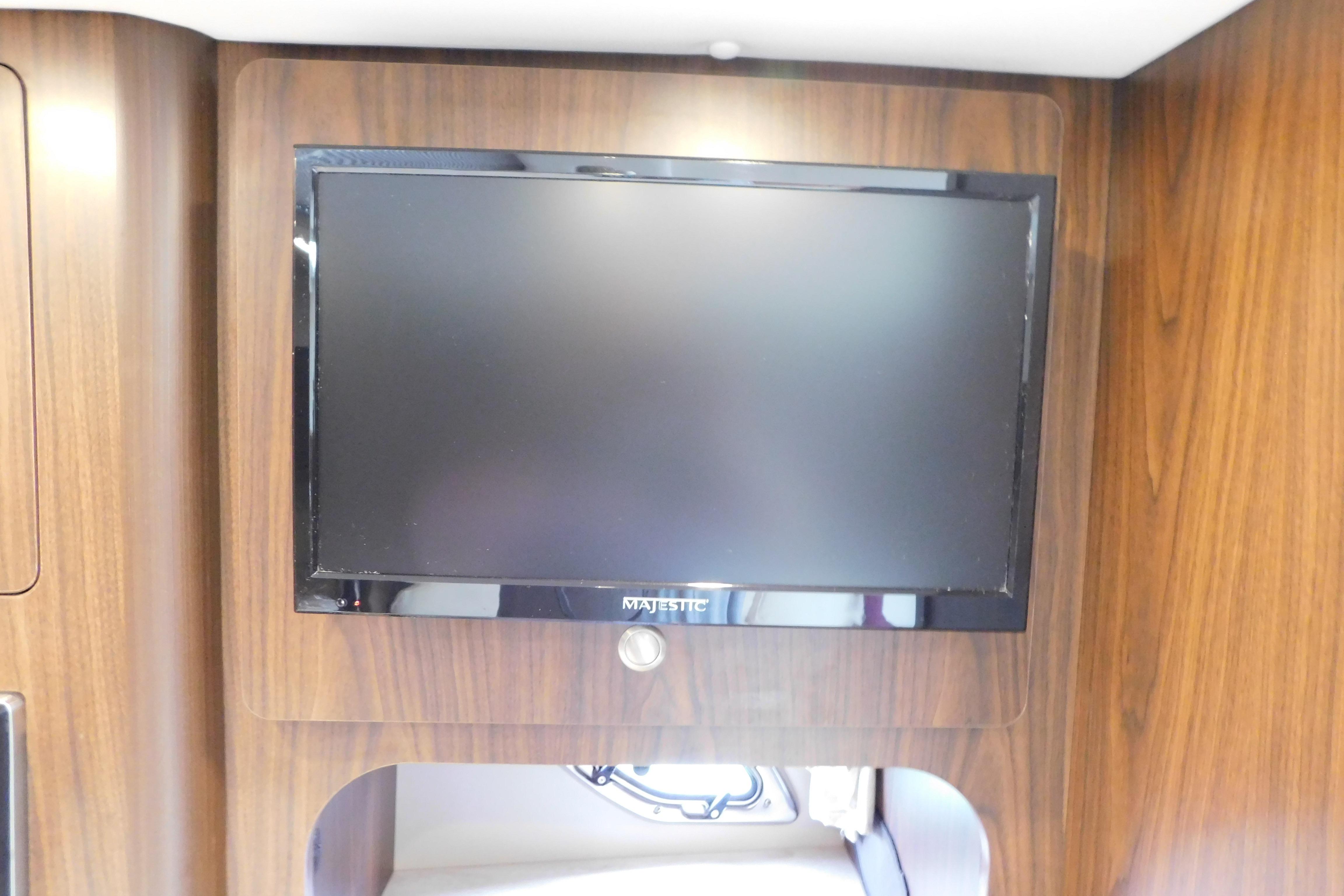 Flat-screen TV mounted on wood paneling inside a 2017 Rinker EX 320 boat.
