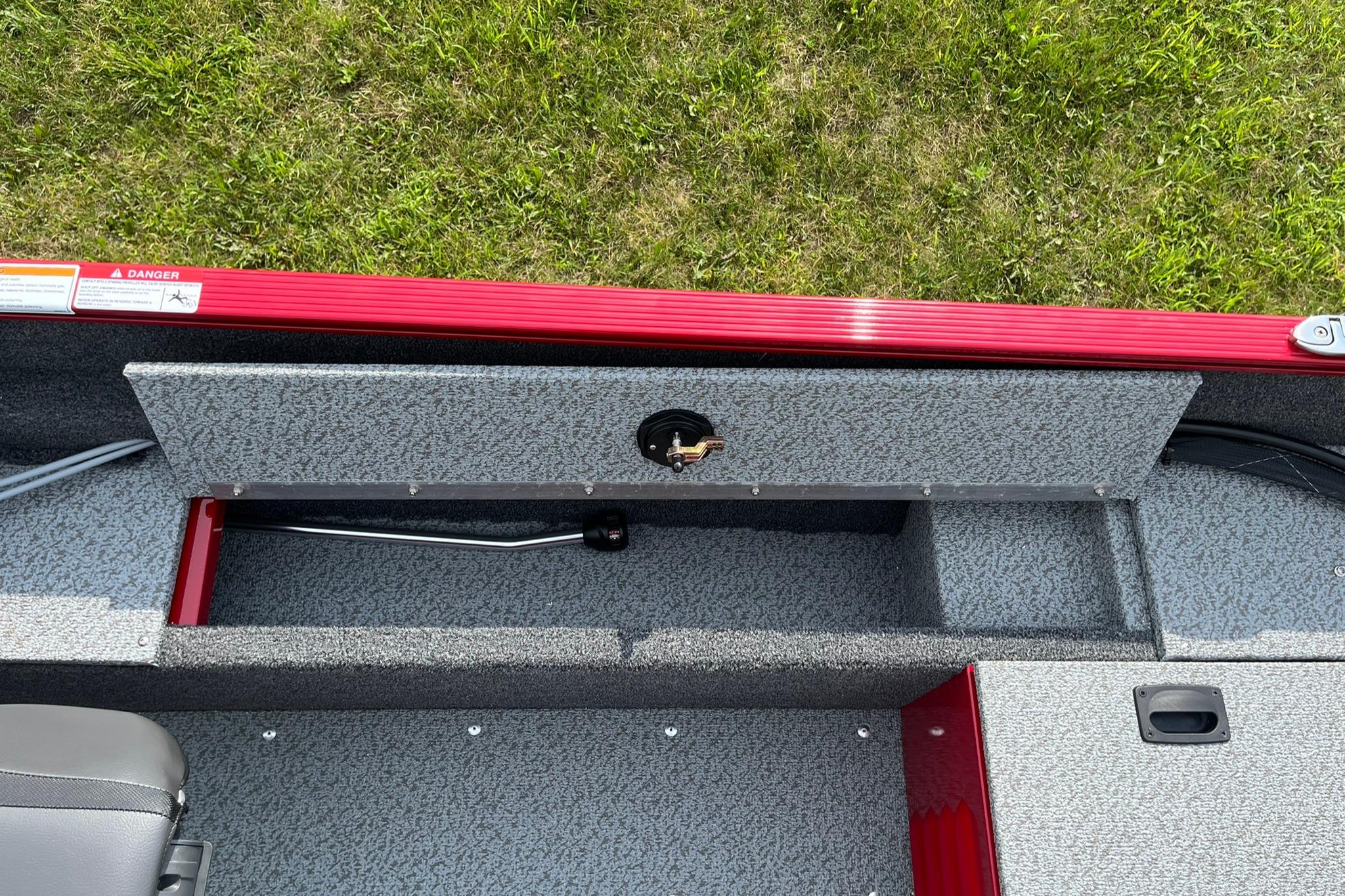 2026 Lund 1650 Angler SS boat interior with storage compartment, red trim, and gray flooring.