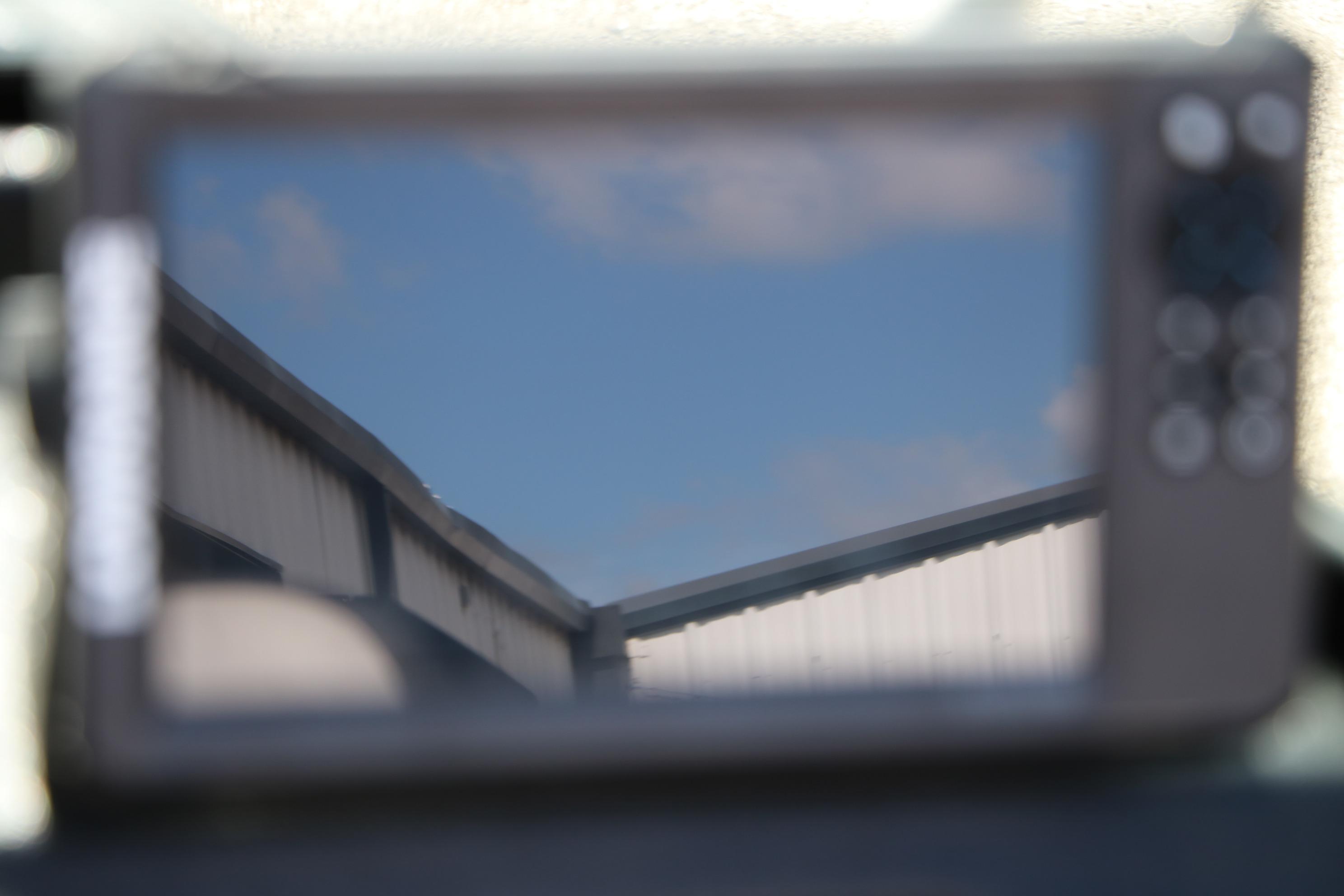 Reflection of a building roof on a screen, clear blue sky background.