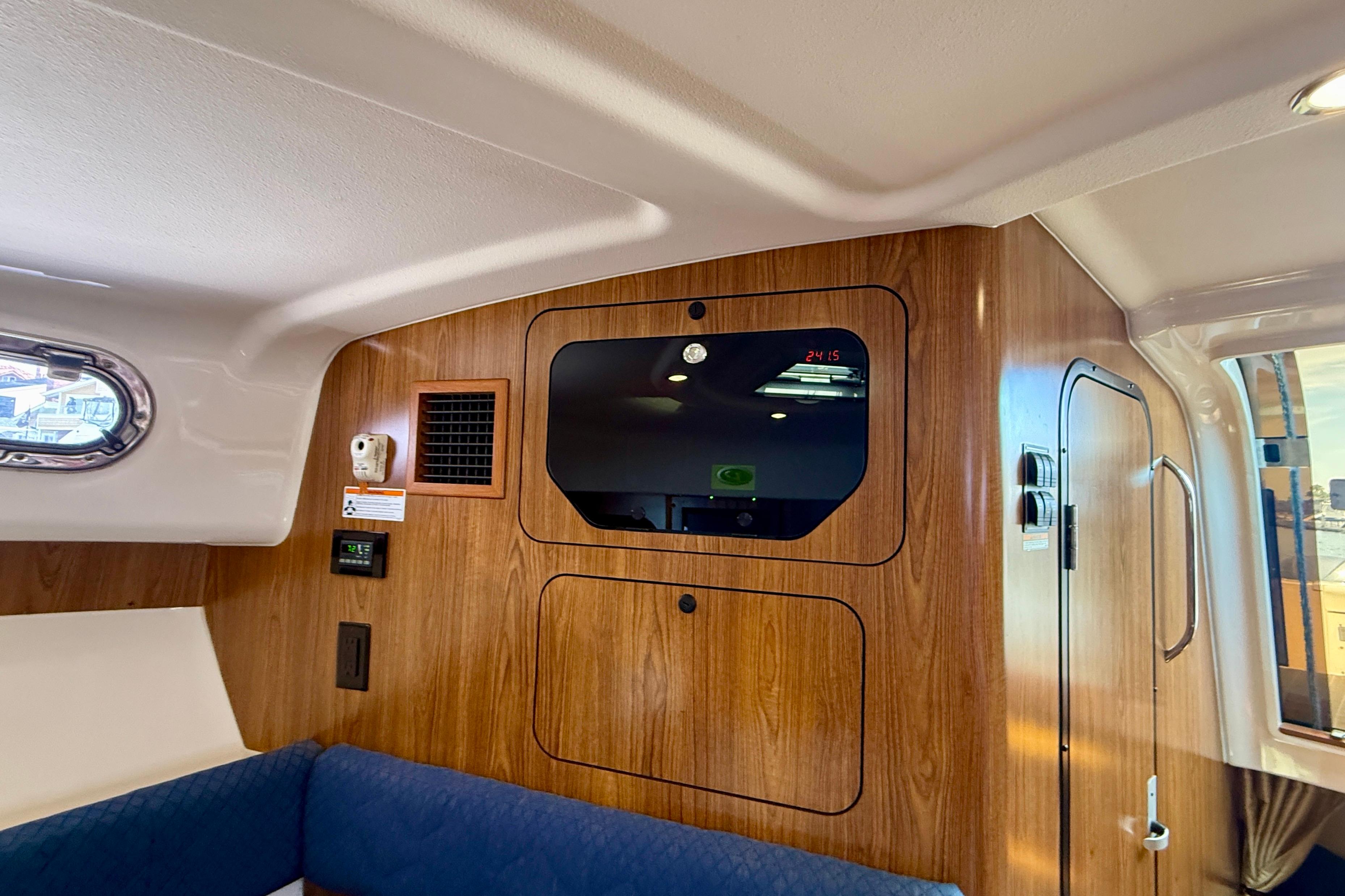 Interior cabin of a 2012 Pursuit OS 345 Offshore boat with wood paneling and seating.