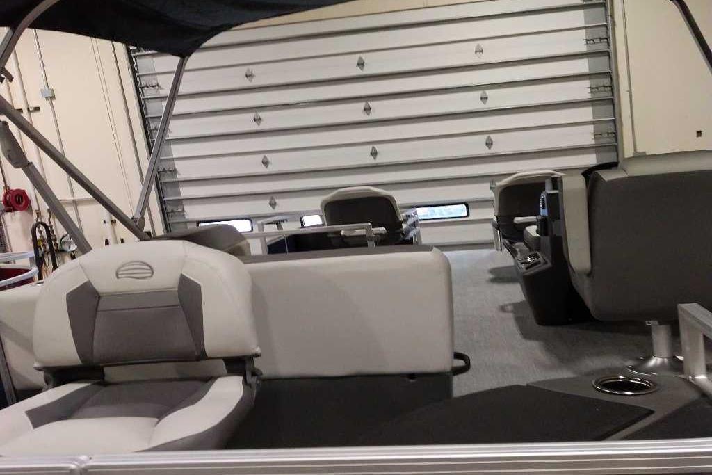 2026 Sun Tracker Bass Buggy 18 DLX interior with seating and storage in a garage.