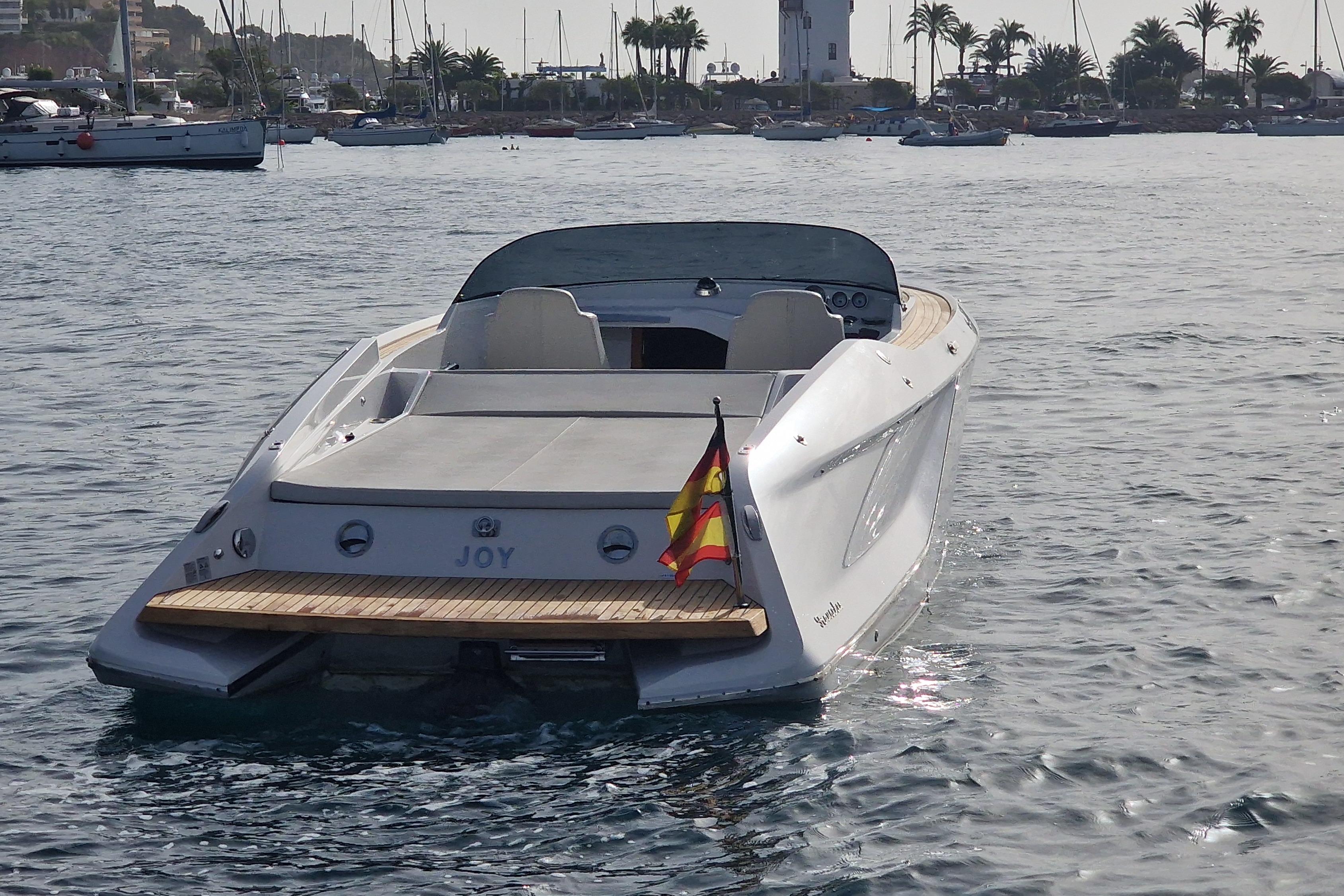 2021 Frauscher 858 Fantom boat on water, rear view with flag, in a marina setting.