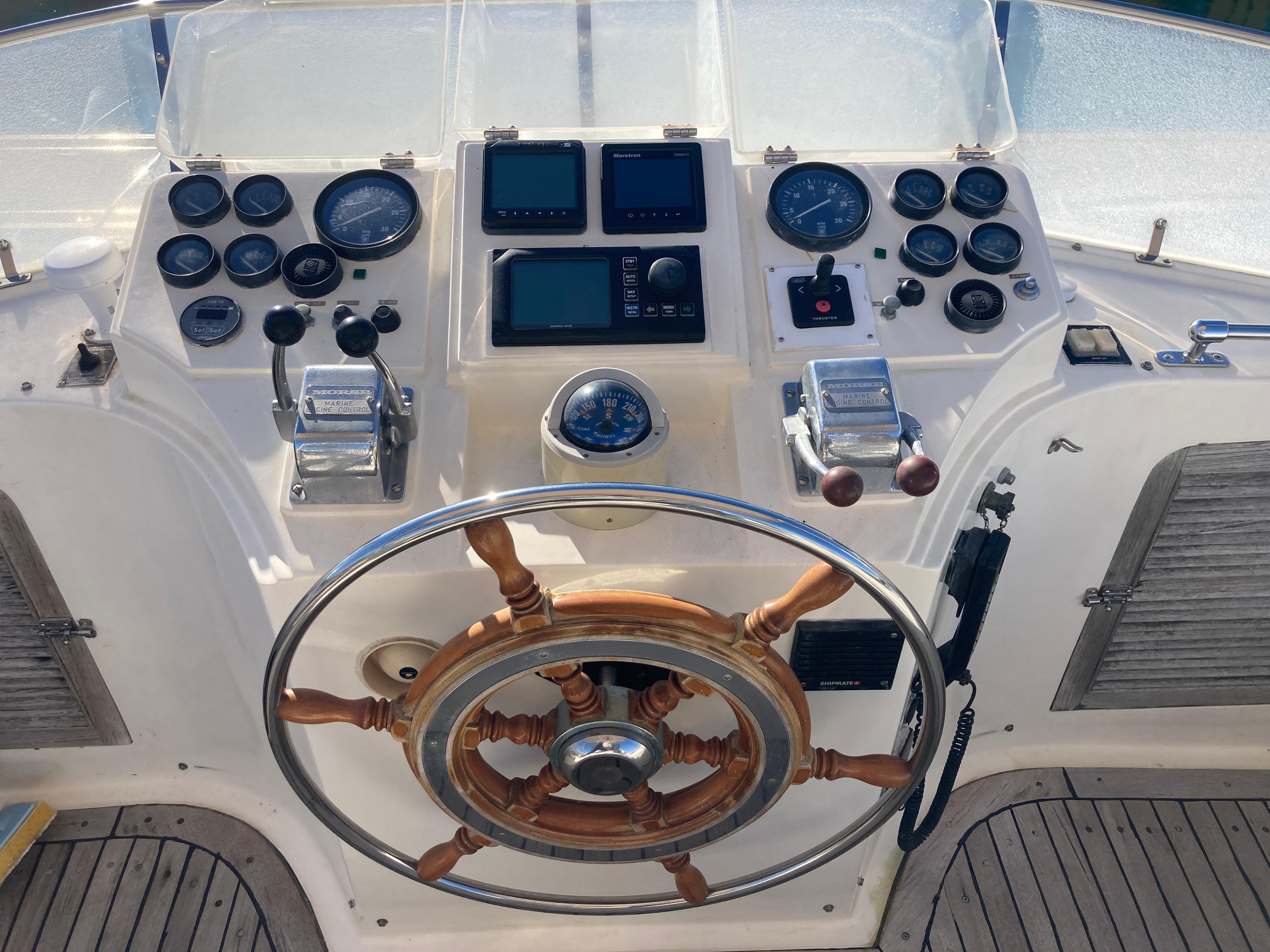 Helm of 1991 Trader 47 yacht with wooden steering wheel and navigation instruments.
