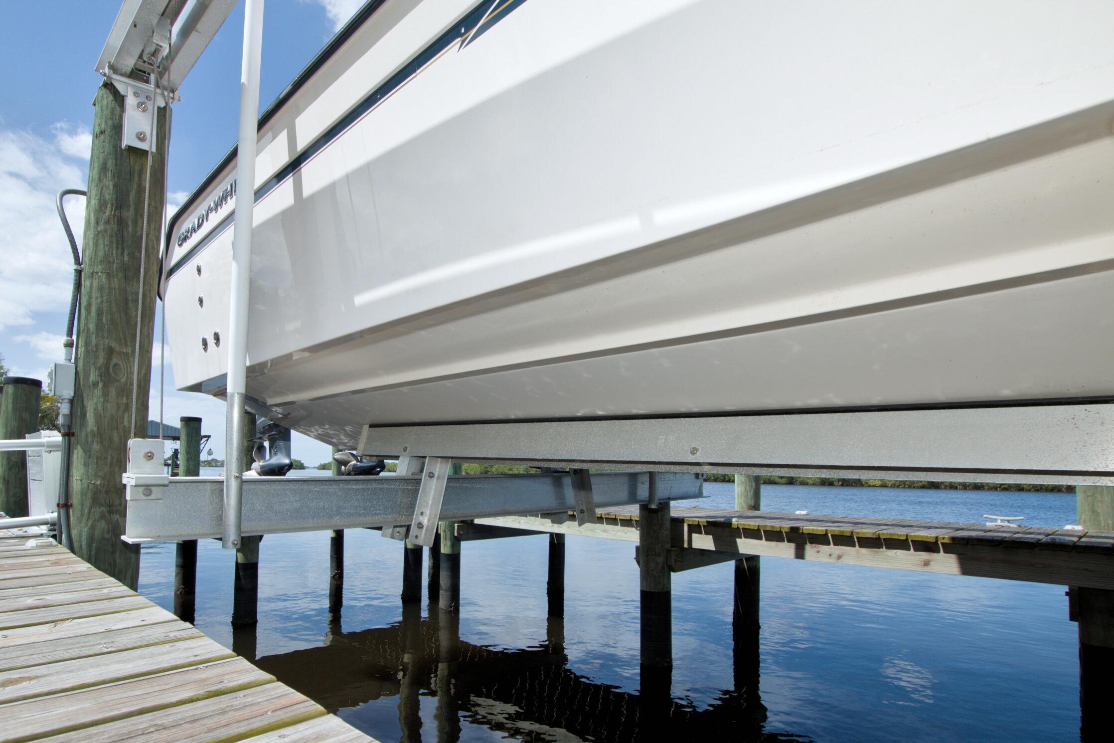 2013 Grady-White Freedom 275 boat on lift at dockside, clear sky background.