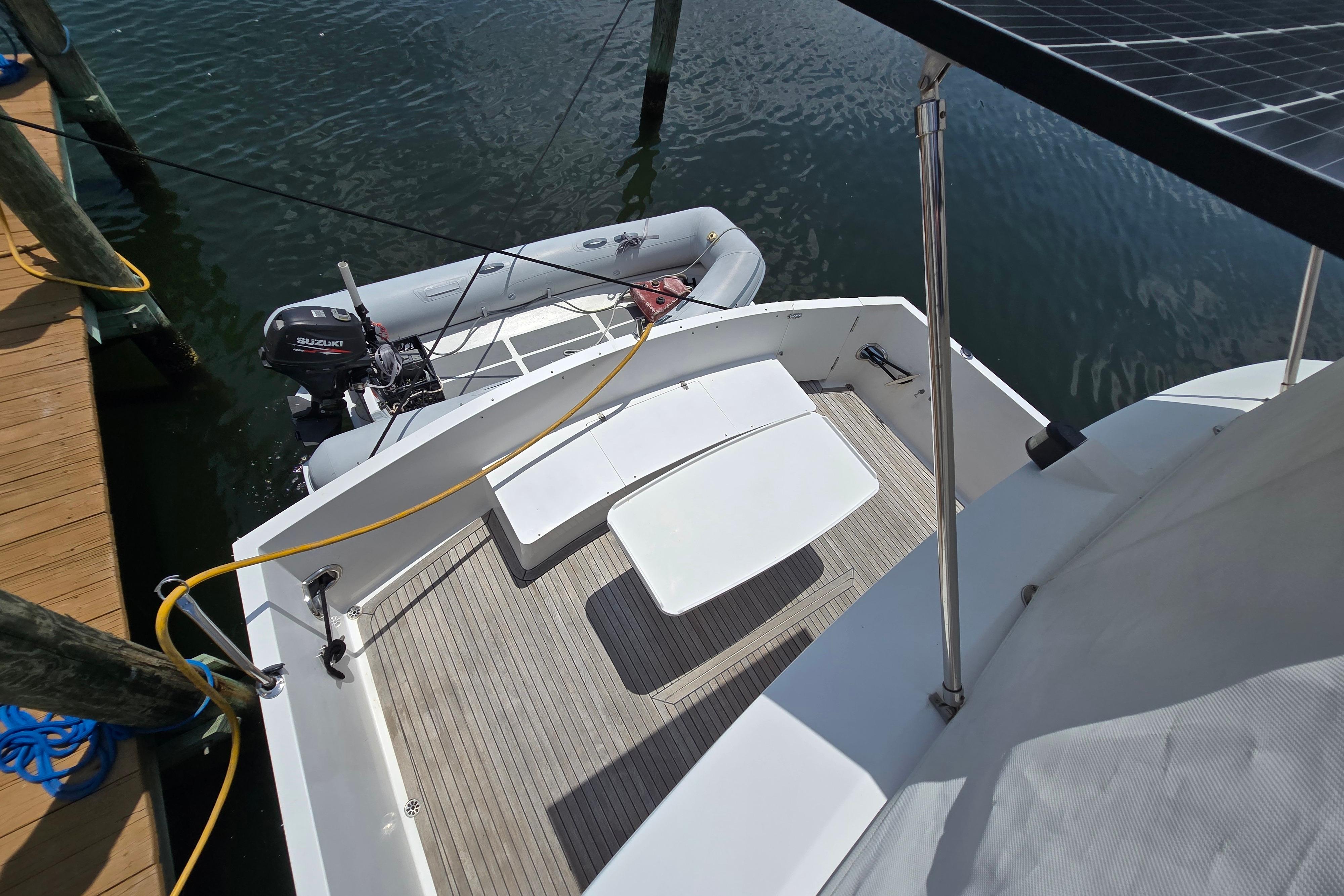 Grand Harbour 58 yacht stern with dinghy and Suzuki outboard motor, docked at marina.