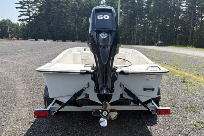 2026 Mako Pro Skiff 15 CC boat with 50 HP engine, parked on gravel.