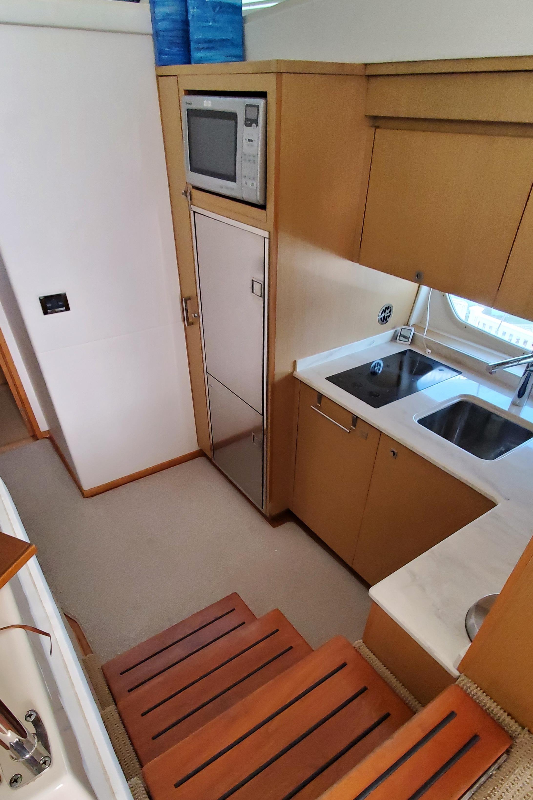 2012 Sea Ray 450 Sedan Bridge kitchen with microwave, sink, and wooden cabinetry.