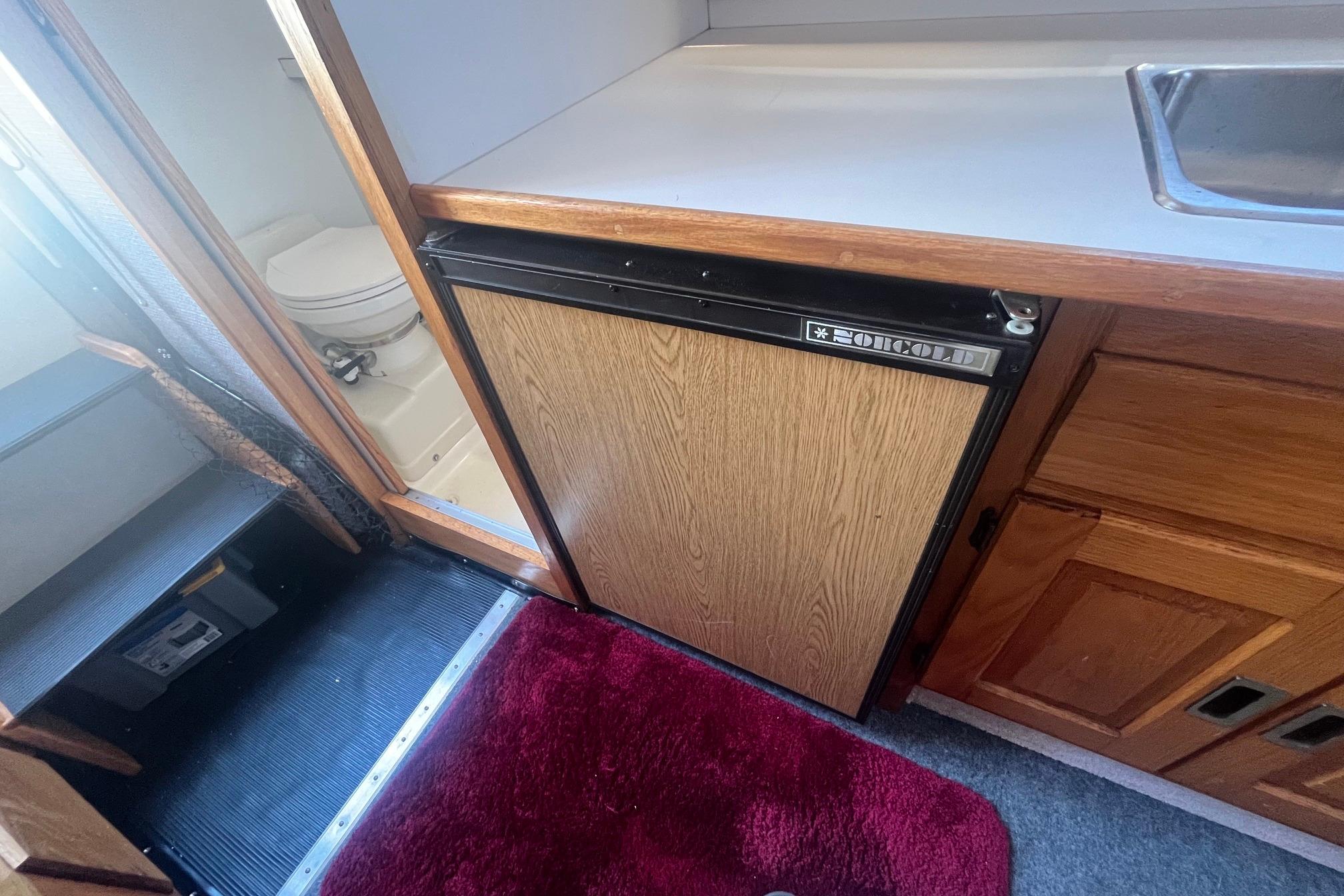 Interior of 1988 Seafox 29 Flybridge with fridge, sink, and bathroom.