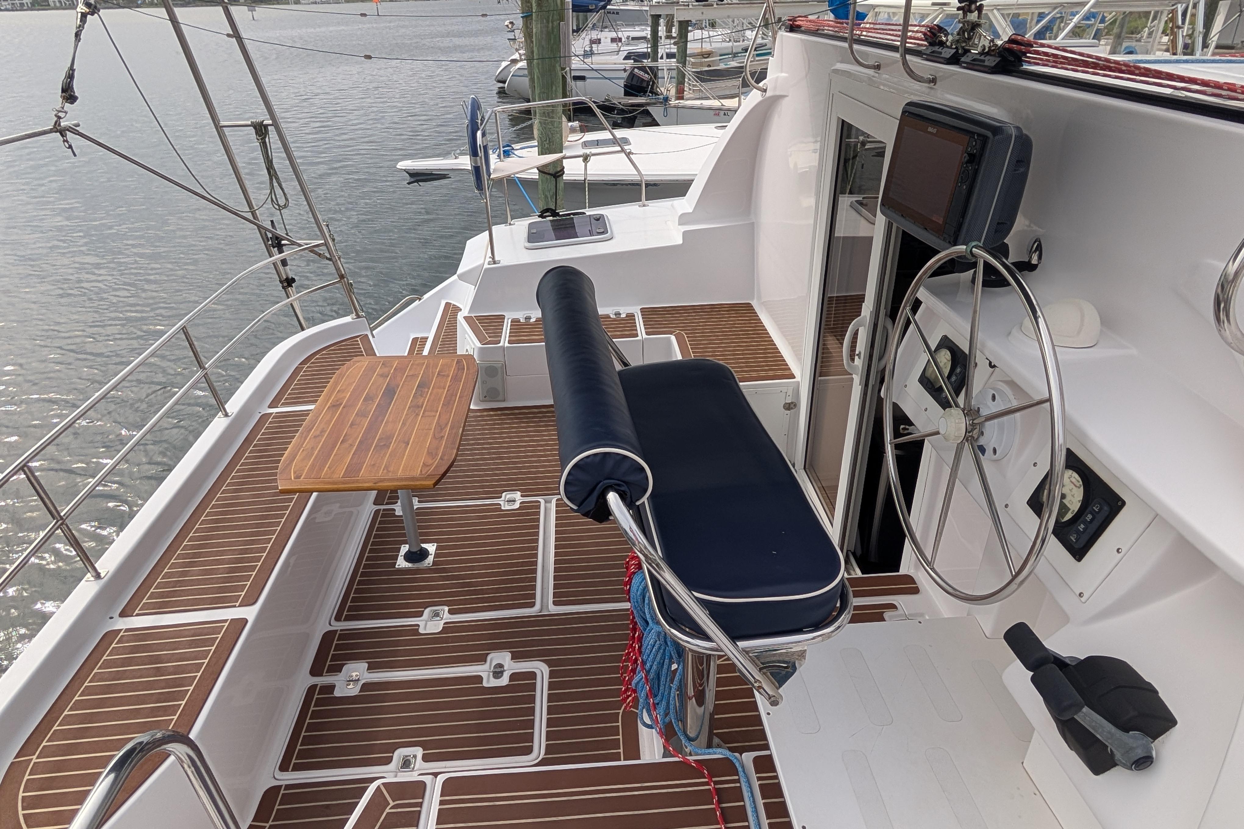 Cockpit of 1999 Island Spirit 37 sailboat with steering wheel and wooden deck.