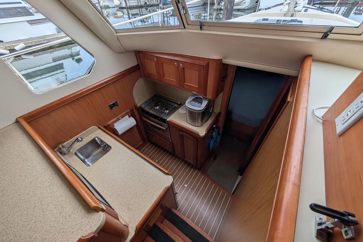 2008 Mainship 38 yacht interior kitchen with wood cabinetry and modern appliances.