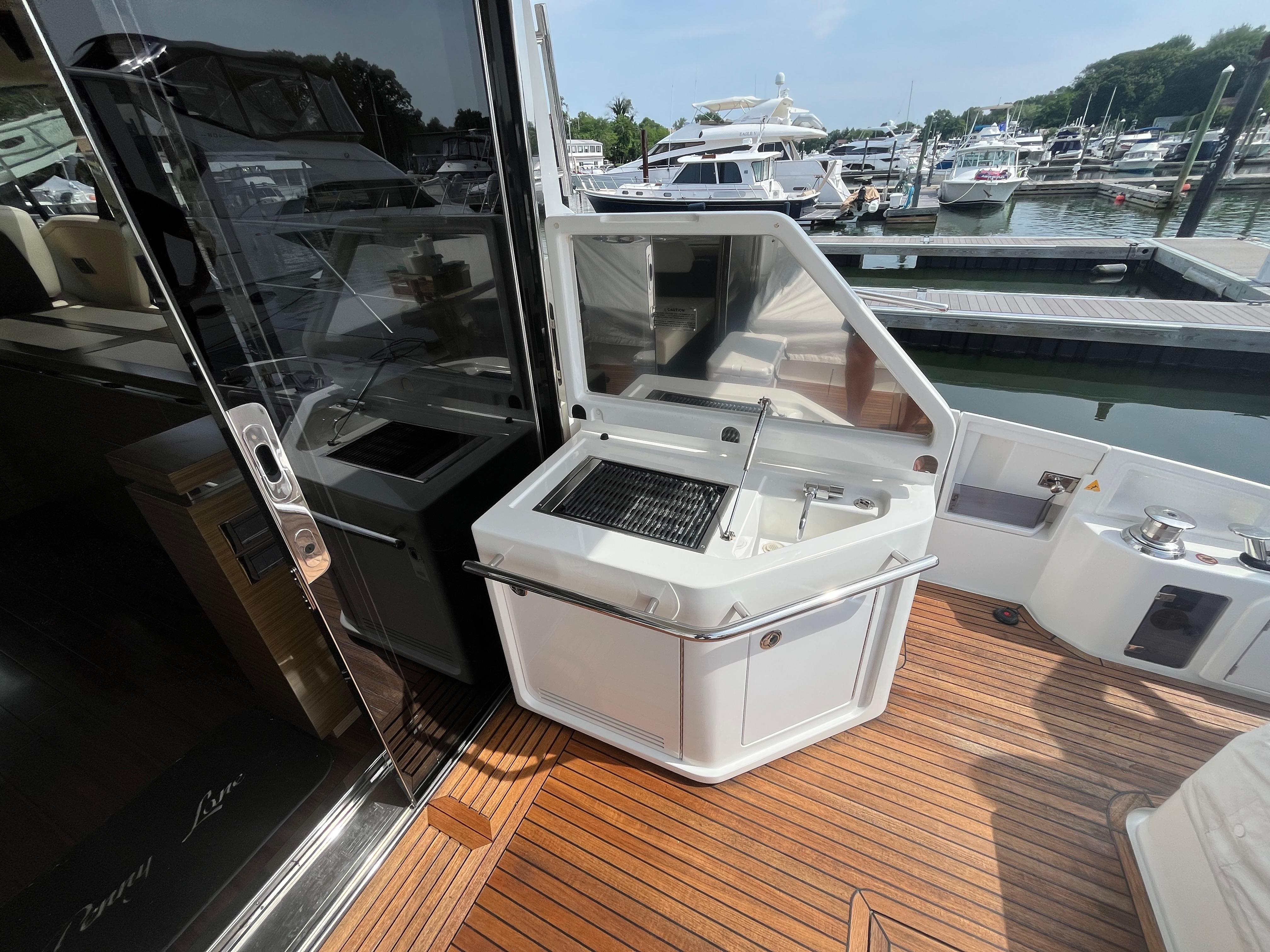 Outdoor kitchen on 2014 Azimut 55S yacht with grill and sink, docked at marina.
