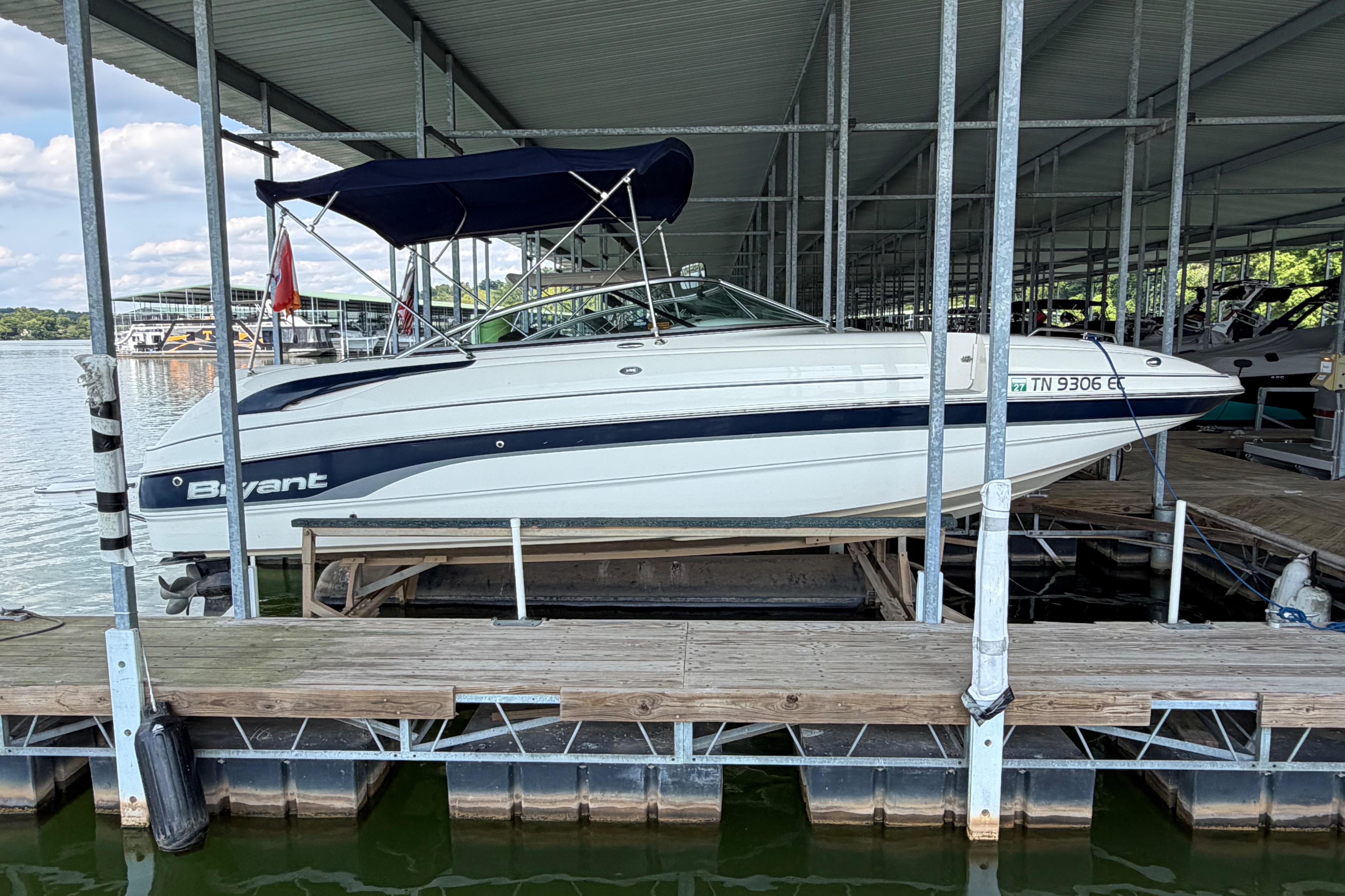 2010 Bryant 255 boat docked under a covered marina on a sunny day.
