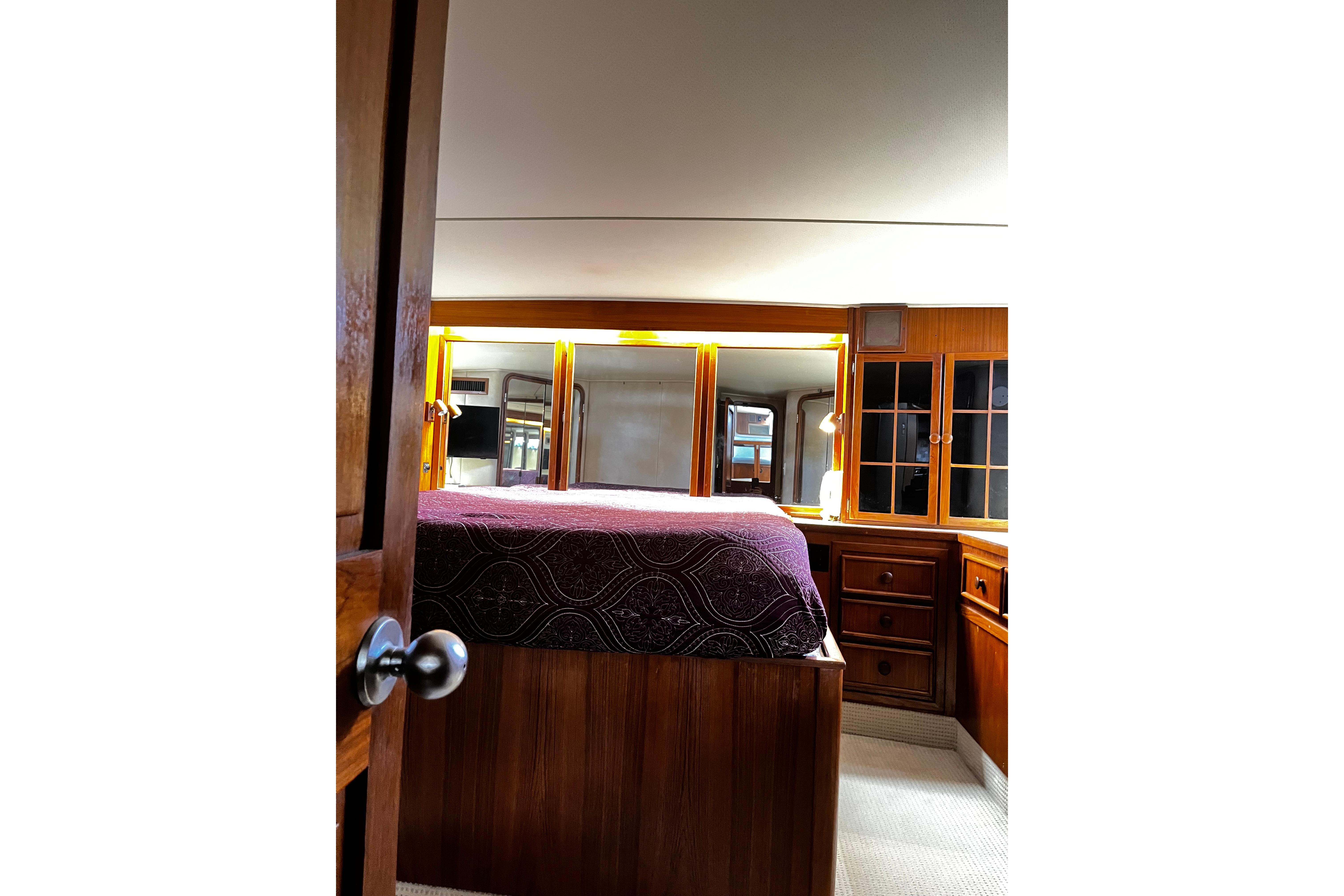 Luxurious 1988 Chris Craft Constellation yacht bedroom with wooden cabinetry and elegant decor.