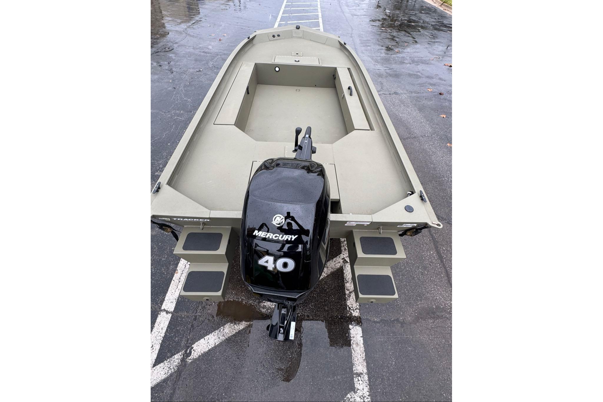 2026 Tracker Grizzly 1654 T Sportsman boat with Mercury 40 engine, parked on wet pavement.