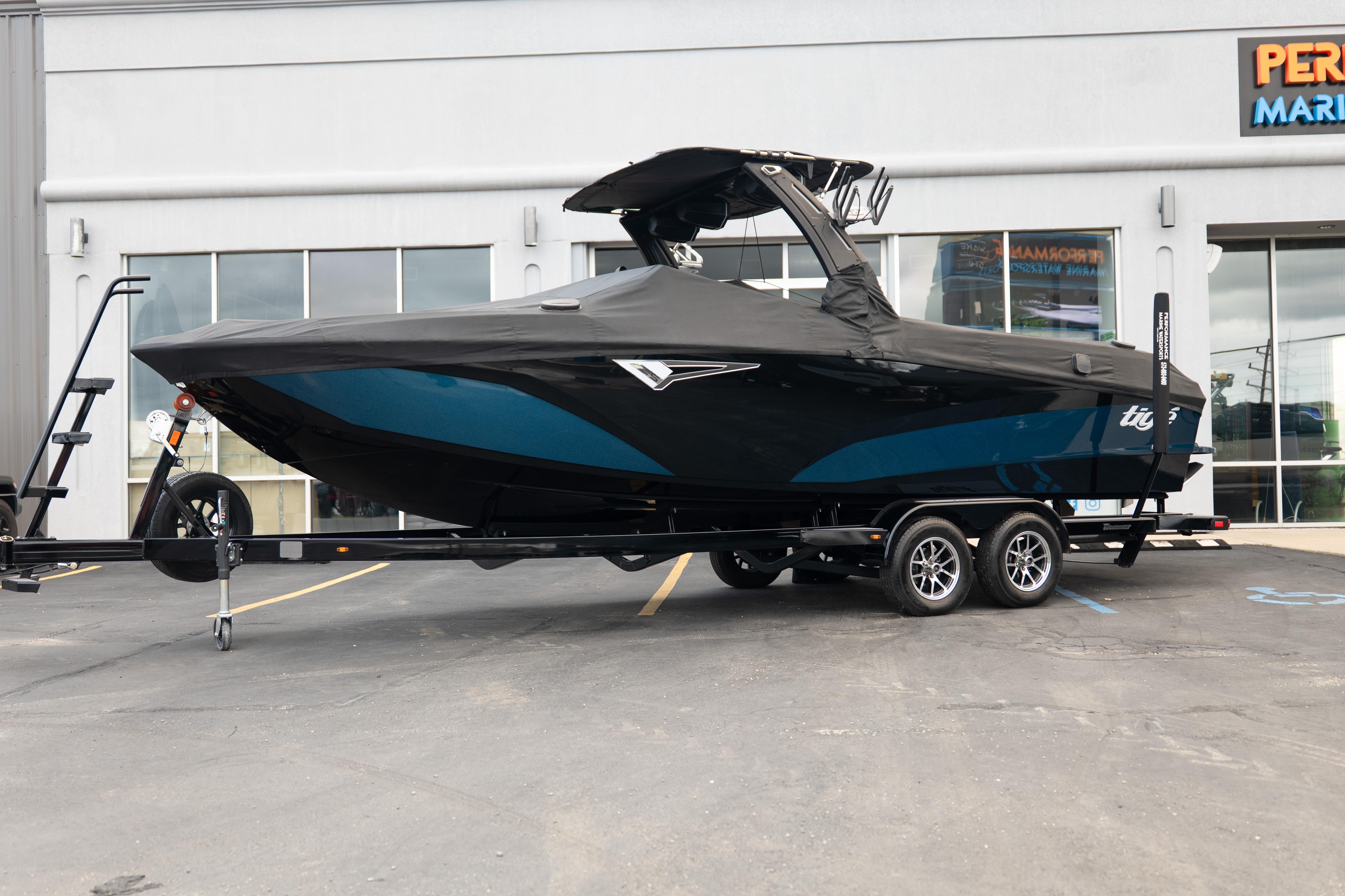 2024 Tigé Z5 boat with cover on trailer, parked outside a marine store.