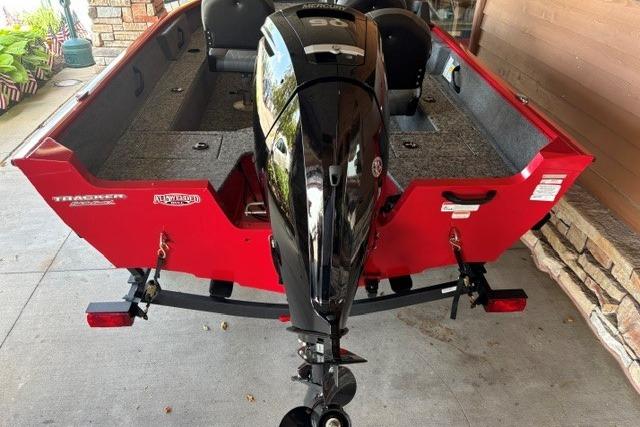 2026 Tracker Pro Guide V-16 SC boat with powerful Mercury engine, red exterior, parked on driveway.