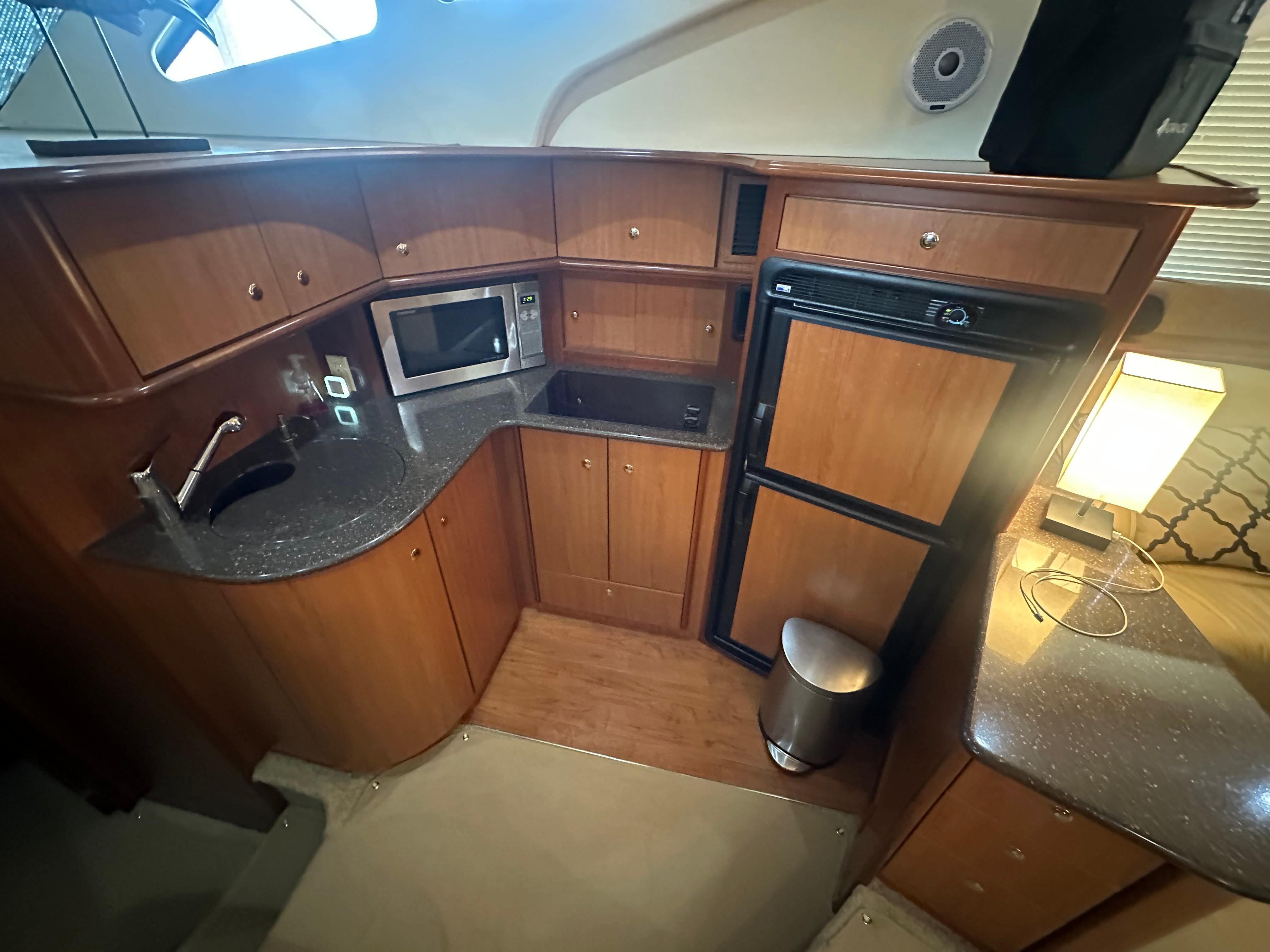 2008 Silverton 35 Motor Yacht kitchen with wood cabinets, microwave, fridge, and sink.