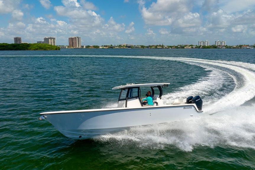 2027 Reef Runner 340 boat cruising on a sunny day with city skyline in background.