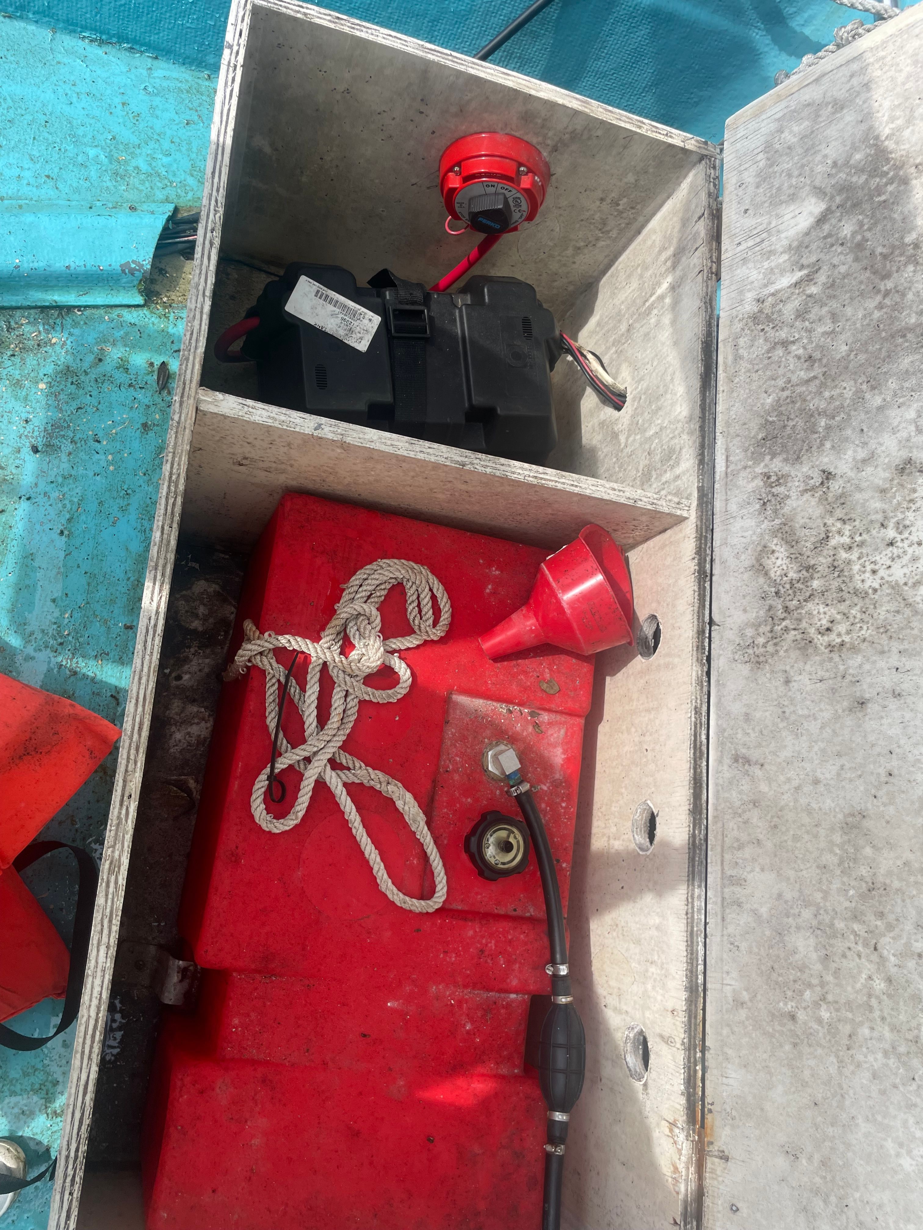 An open boat compartment with red canisters and ropes.