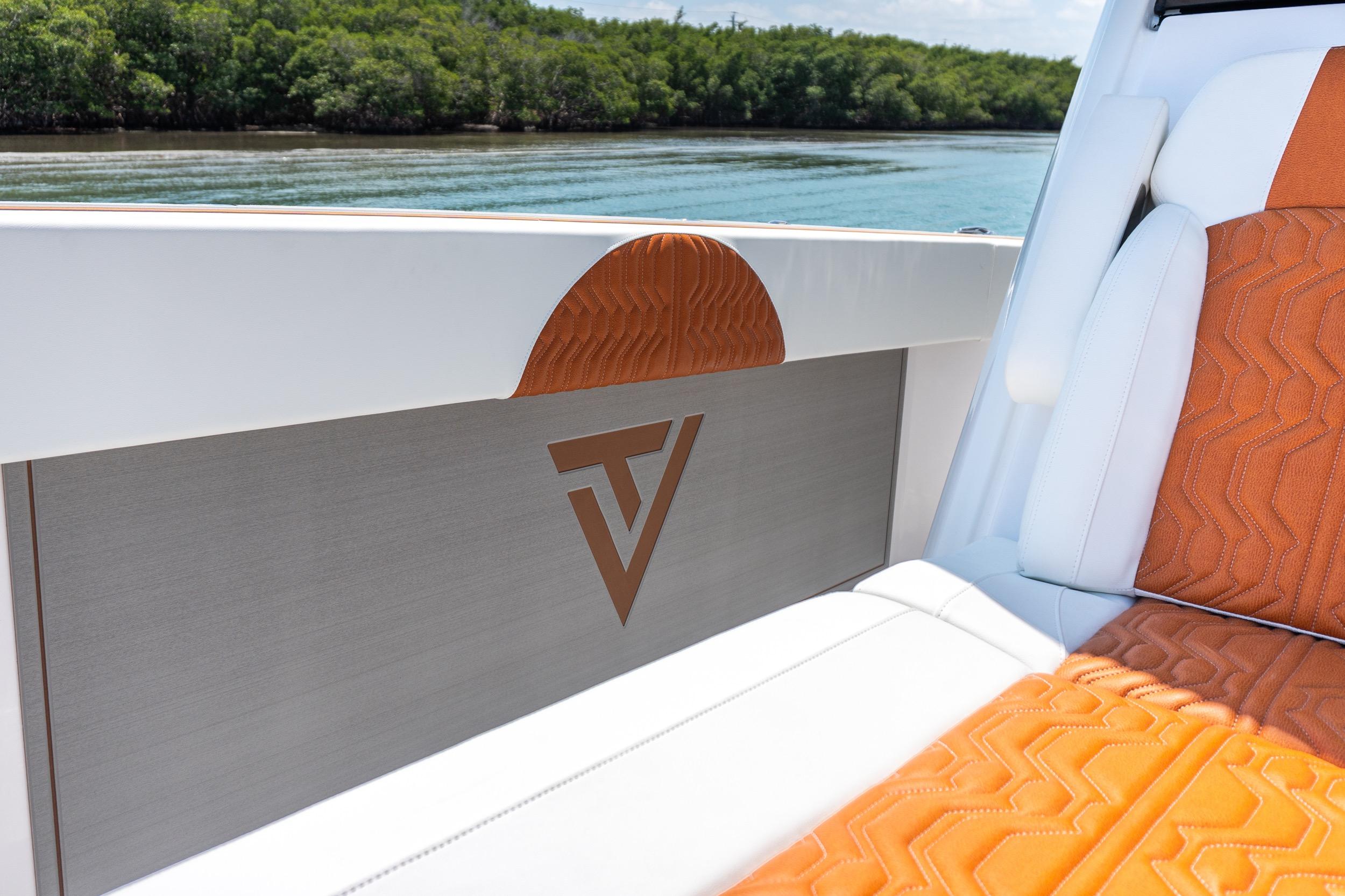 2026 Twin Vee 400 GFX2 CC boat interior with orange and white seating, scenic water view.