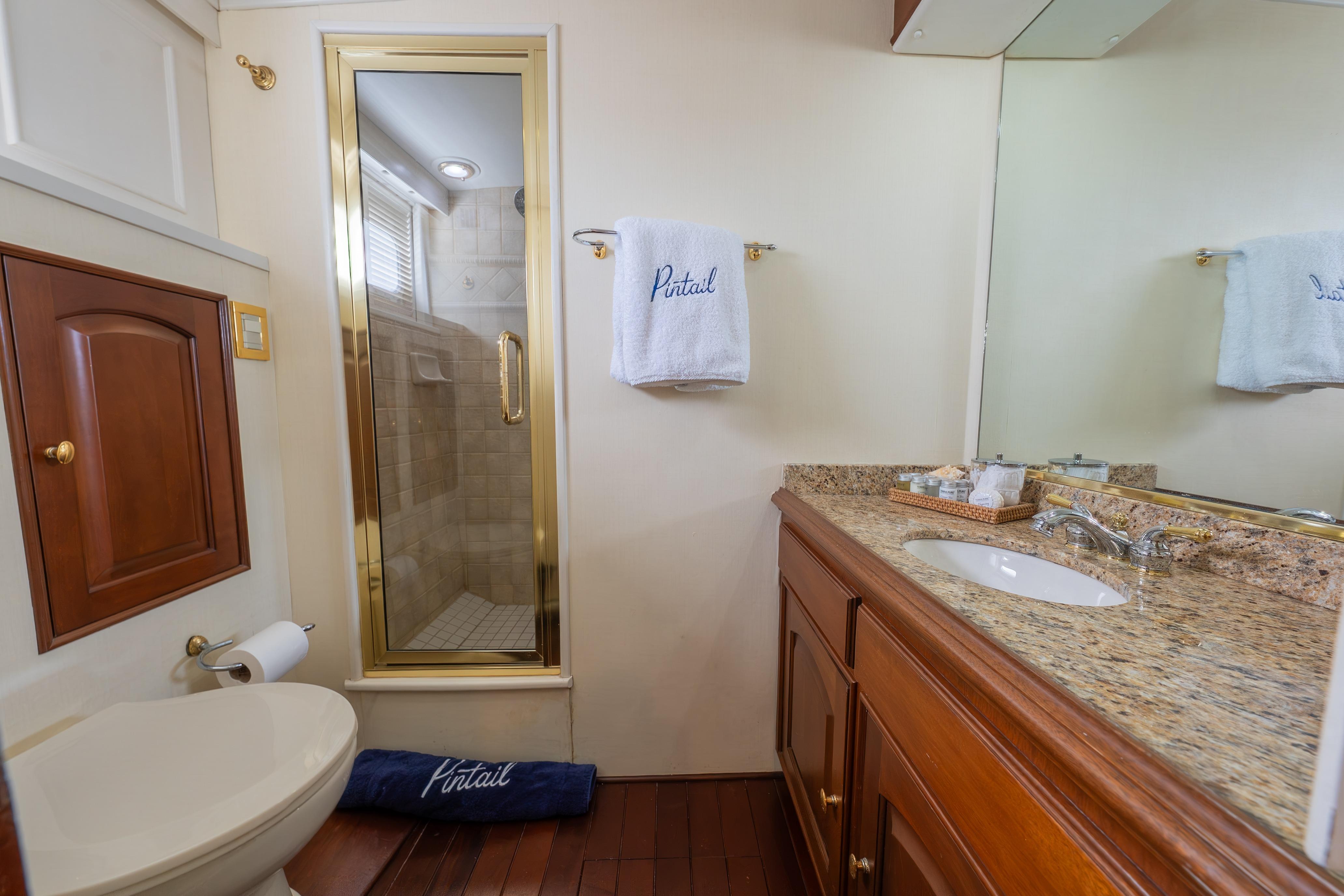 Luxurious 1963 Trumpy Classic yacht bathroom with granite countertop and glass shower.