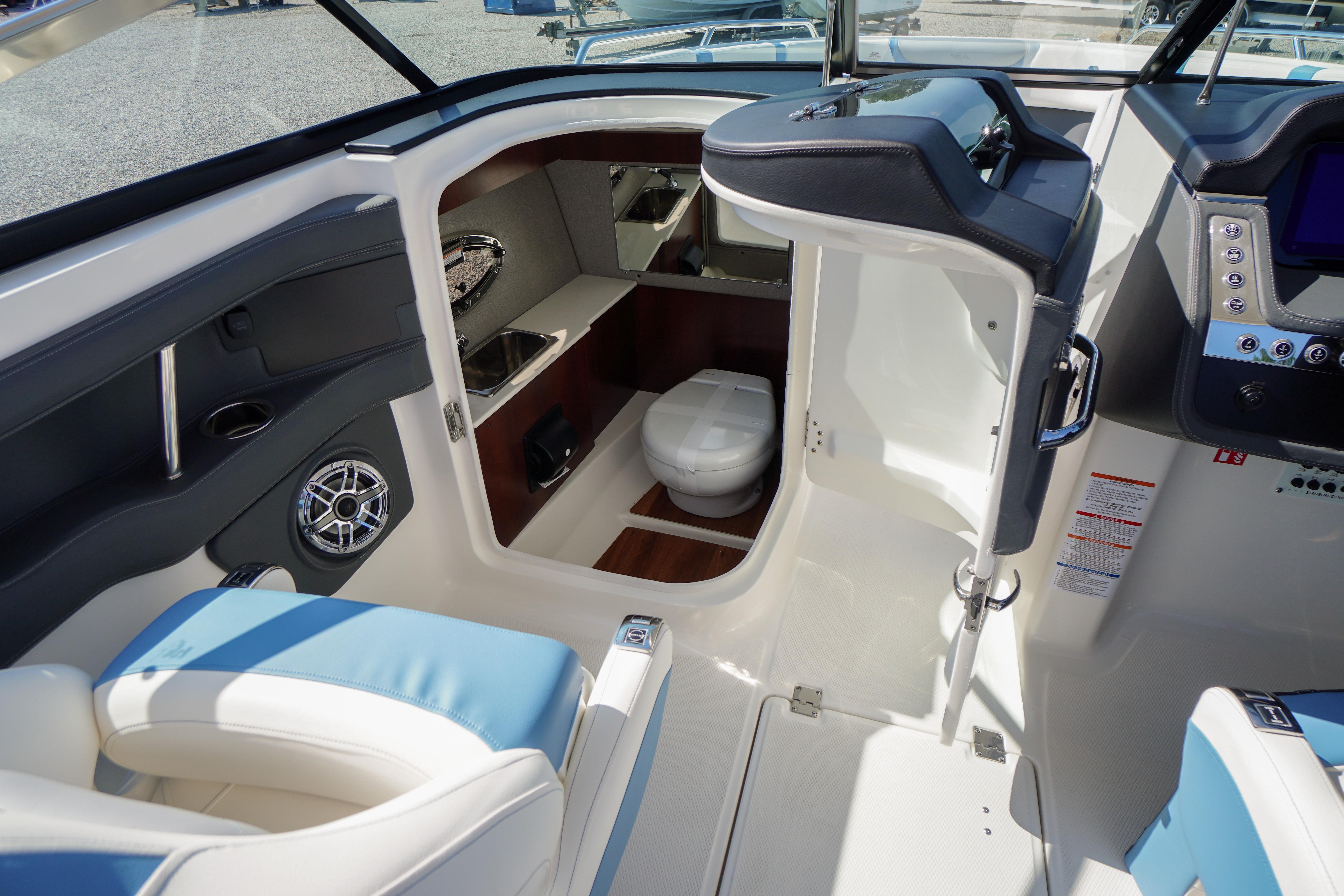 2026 Chaparral 270 OSX boat interior with helm, seating, and compact cabin toilet.