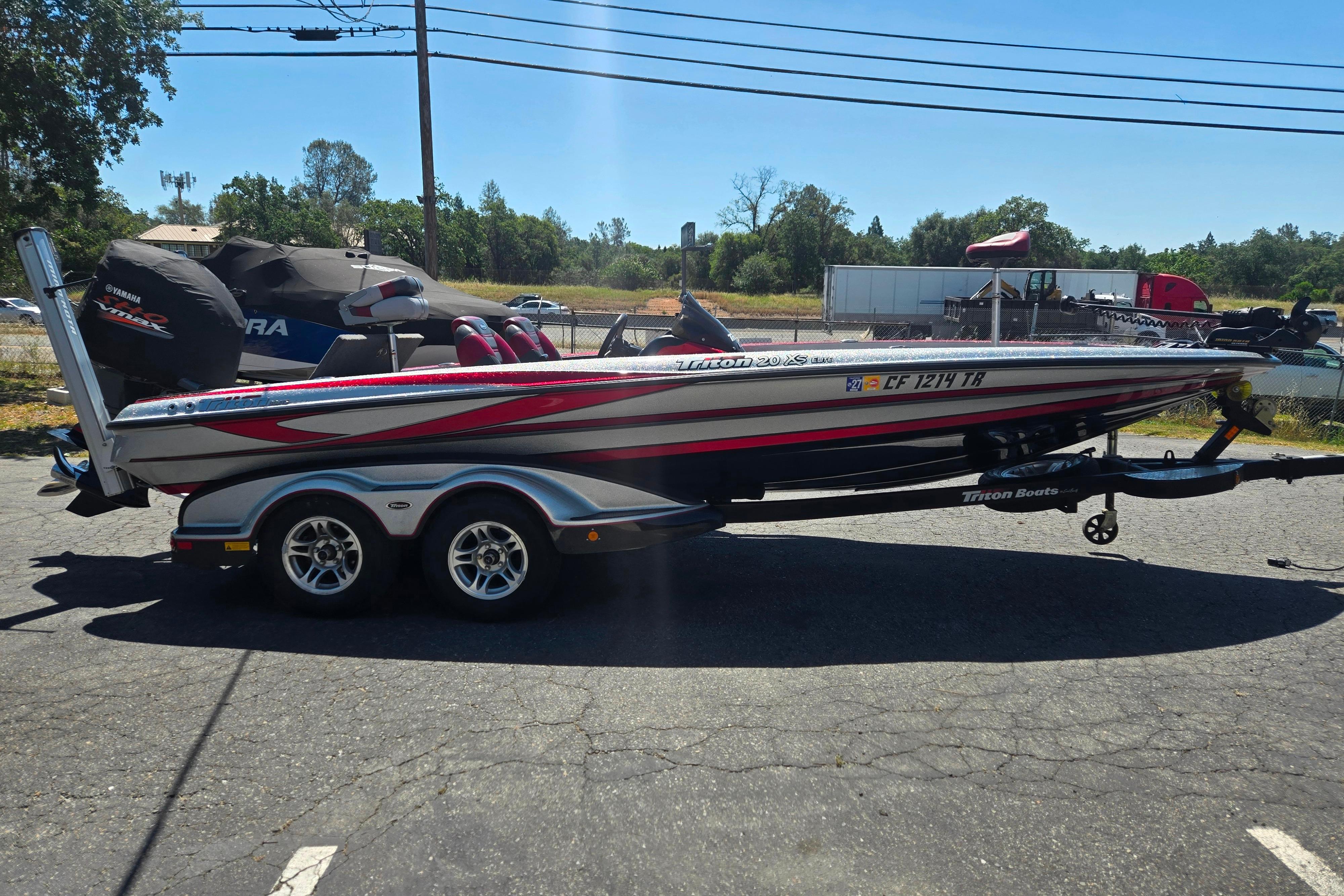 2011 Triton 20XS DC boat on trailer, parked outdoors under clear sky.