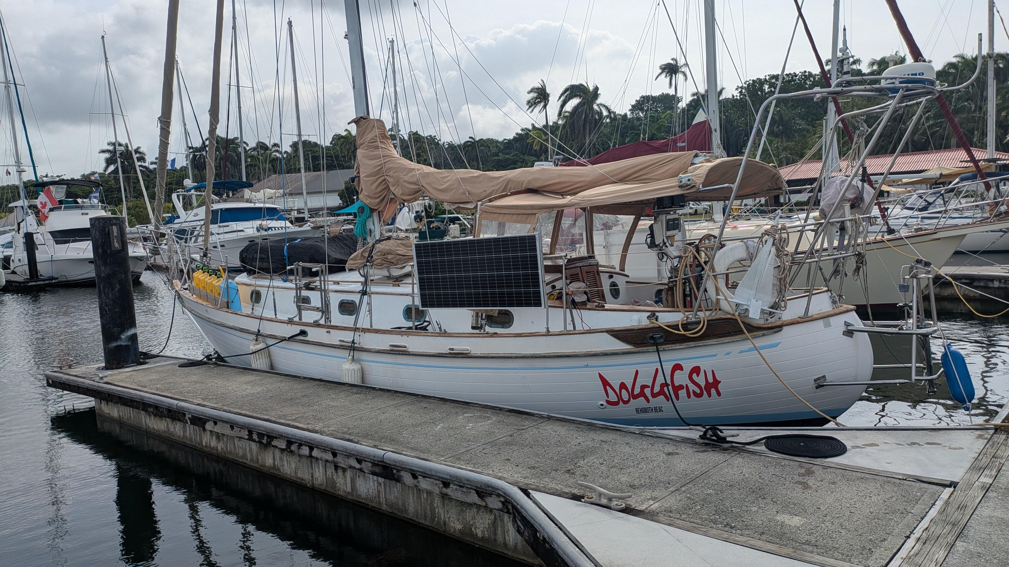 1986 Tayana 37 sailboat docked at marina with solar panel and covered sails.