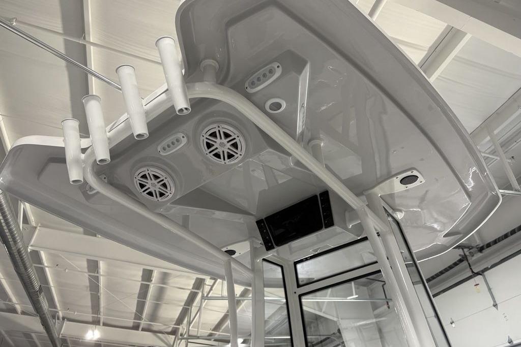 2026 Tidewater 2210 Carolina Bay boat T-top with rod holders and speakers in a showroom.