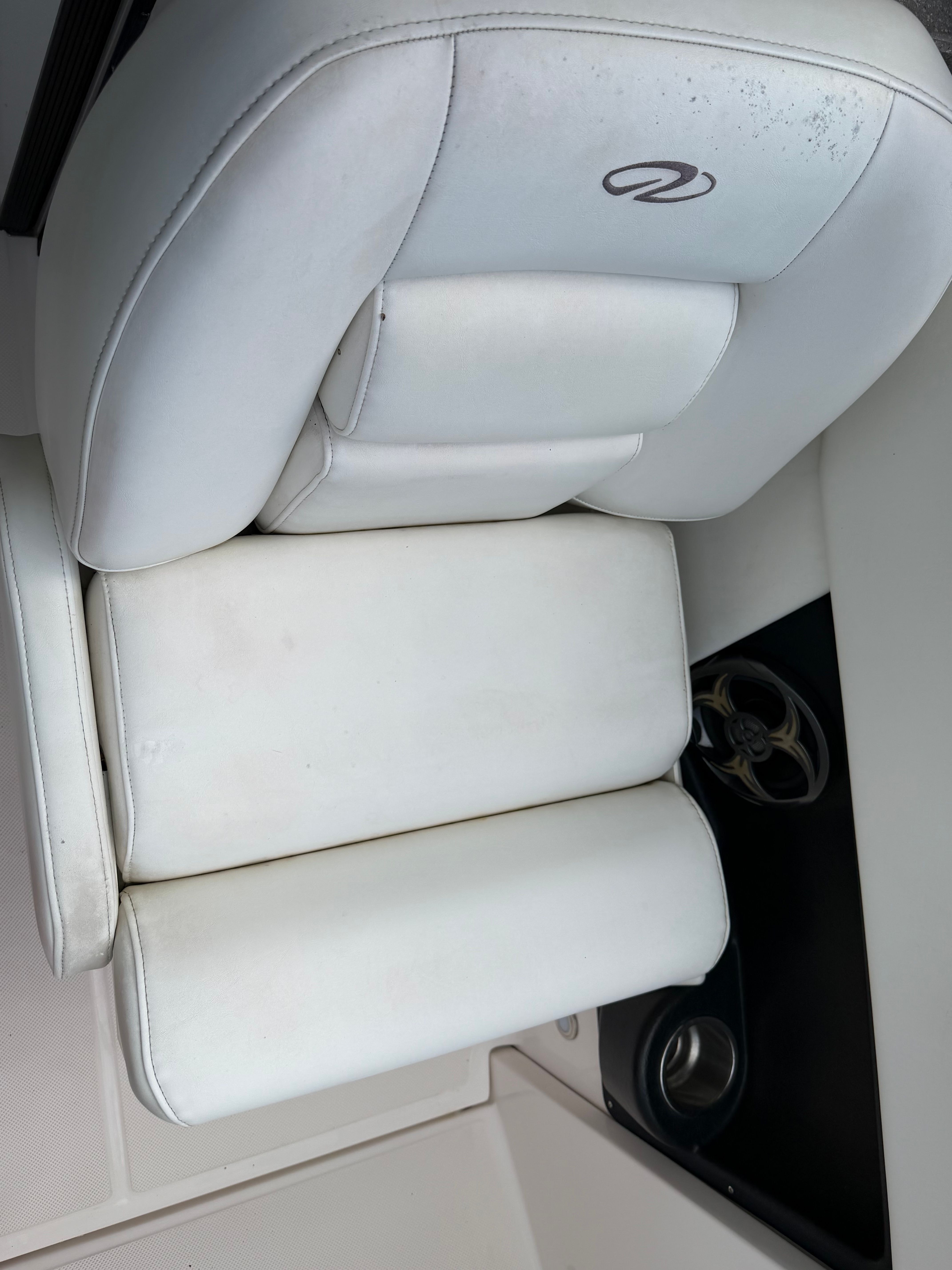 A white cushioned seat with padded design and a cup holder beside it.