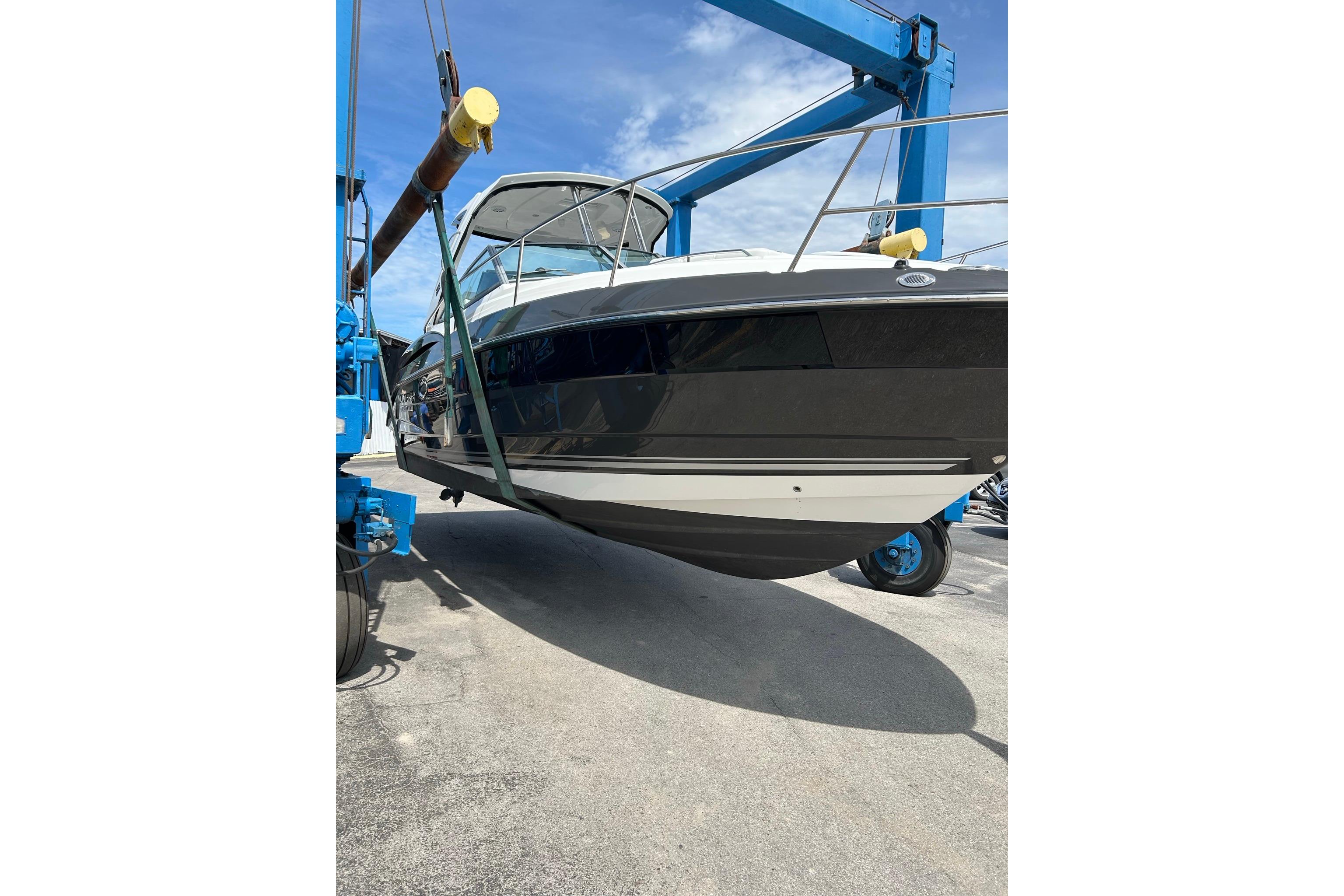 2019 Monterey 335 Sport Yacht being lifted by a blue crane under a clear sky.