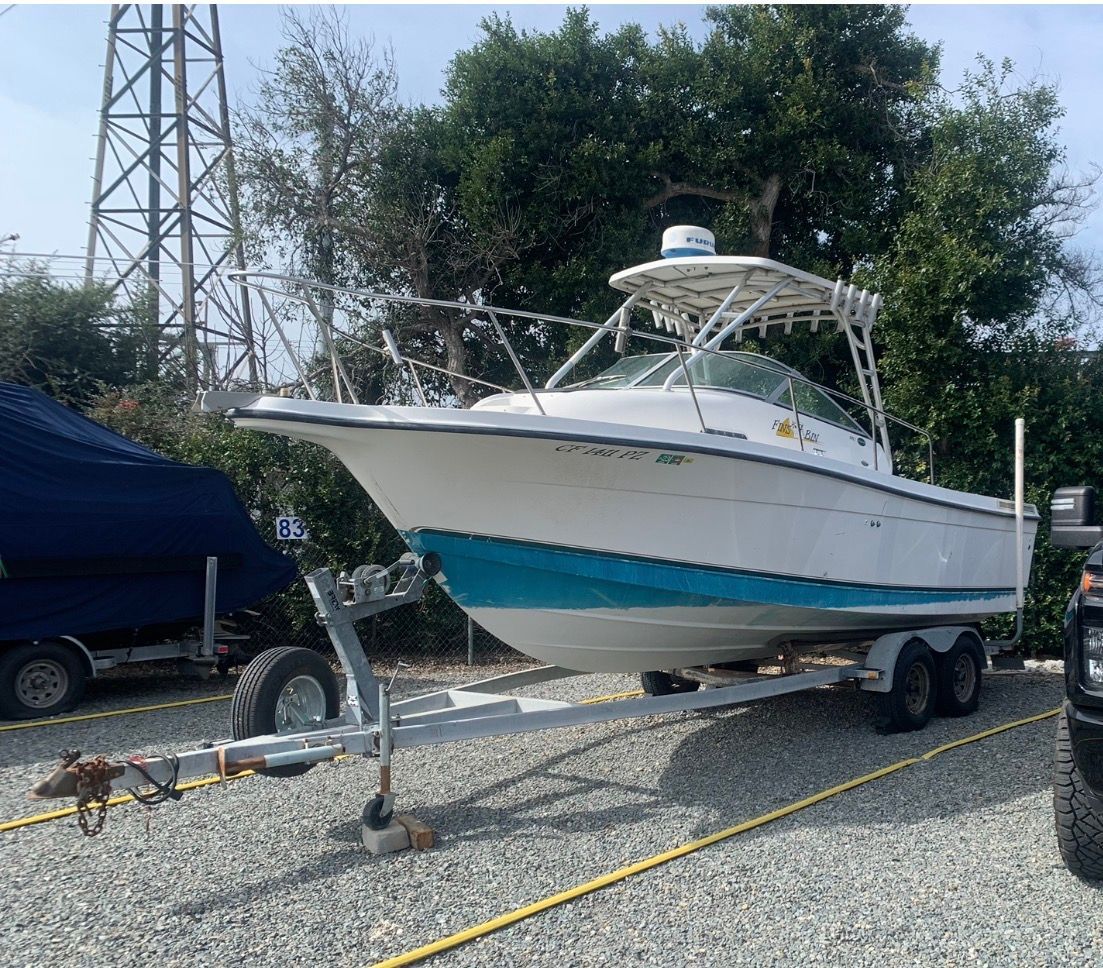A 2003 Bayliner Walk Around Cuddy Cabin boat on a trailer in a gravel lot.