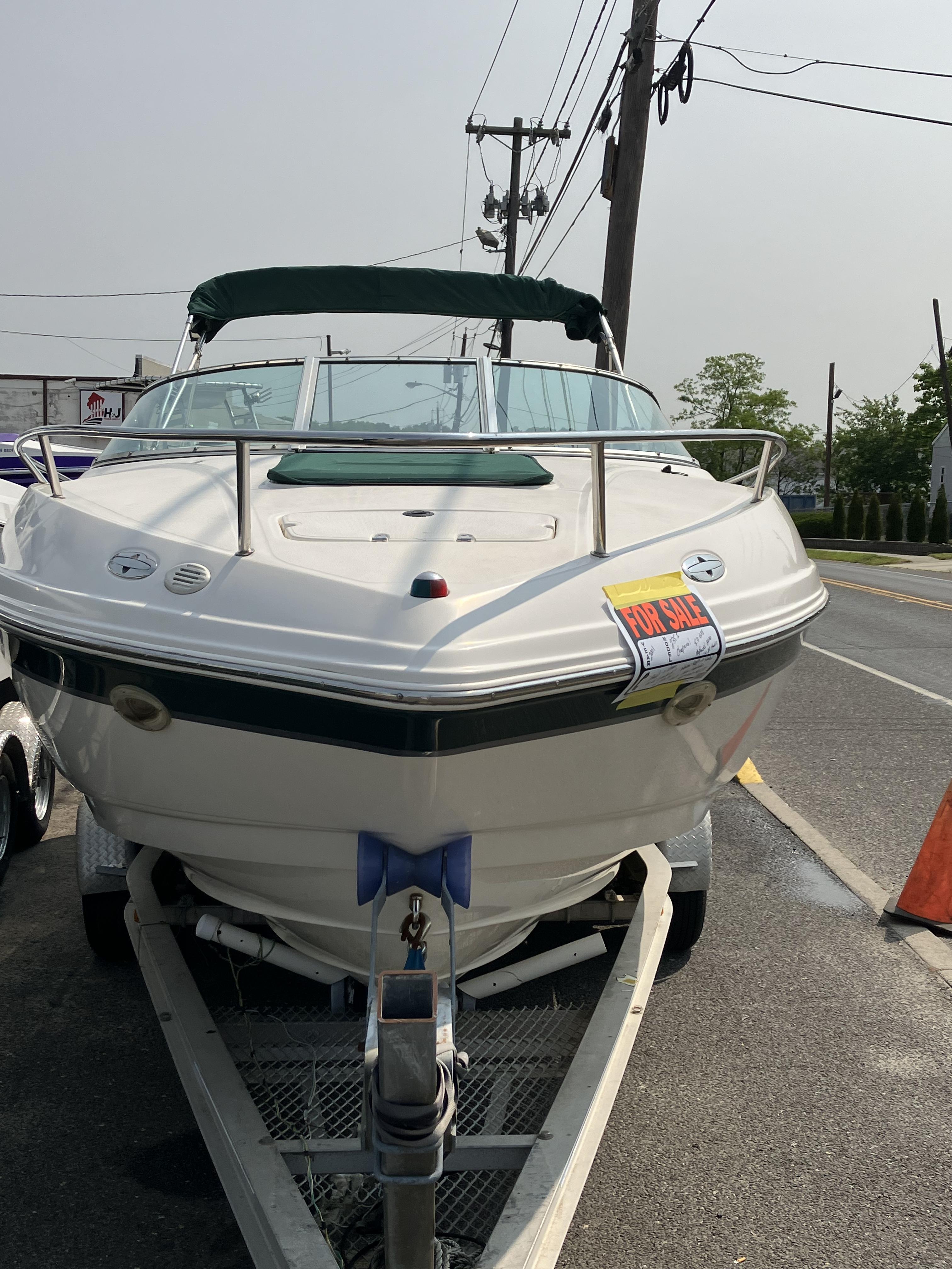 A 2001 Chaparral 235 SSi boat is on a trailer by a roadside.