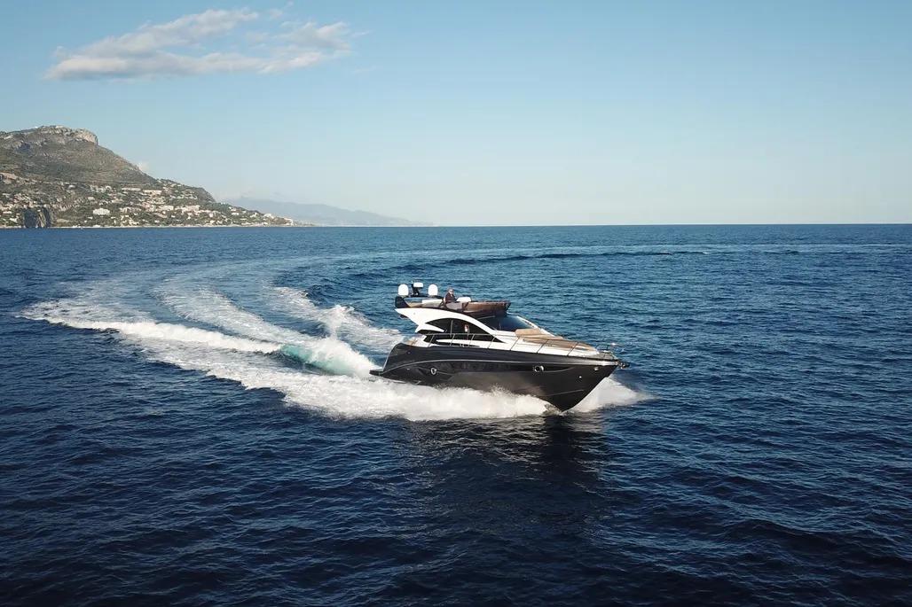 2025 Cobrey 52 FLY yacht cruising on open sea with scenic coastal backdrop.