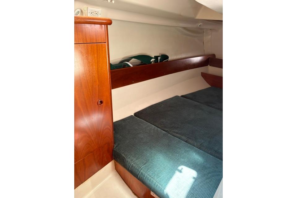 Interior cabin of 2000 Beneteau Oceanis 321 sailboat with wooden cabinetry and cushioned seating.