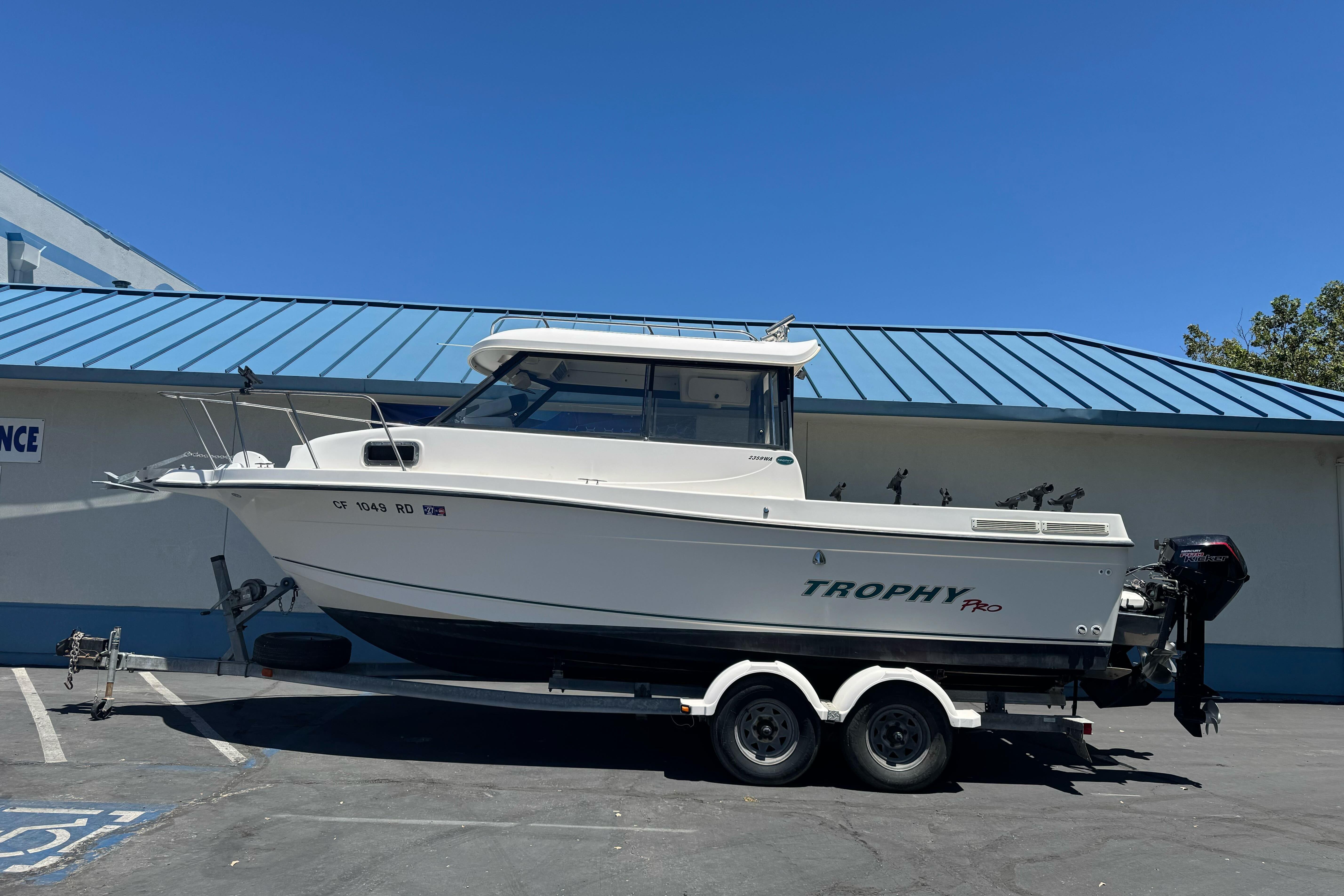 A 2004 Trophy 2359 WA boat on a trailer in front of a building with a blue roof.