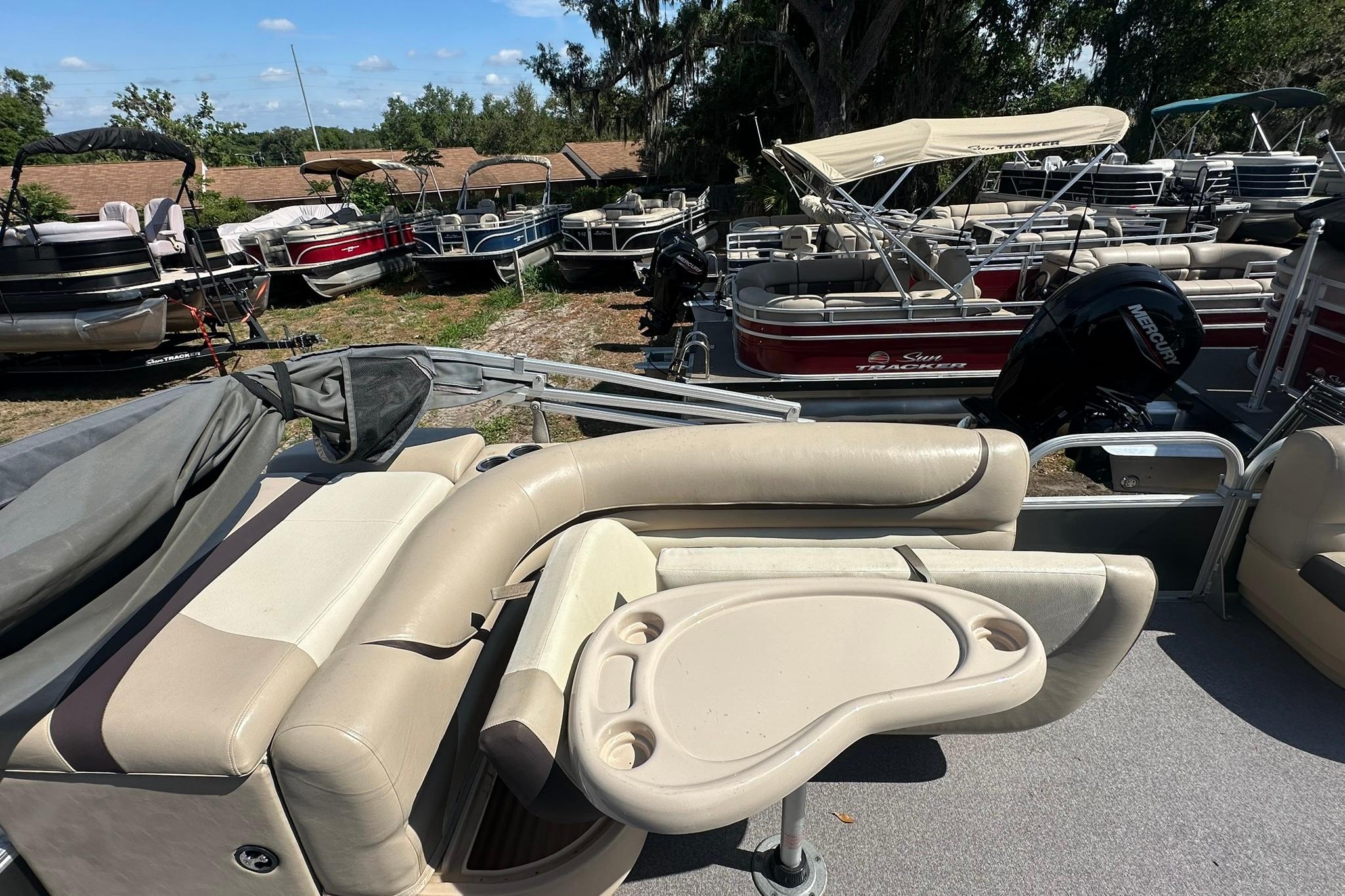 2016 SUNTRACKER Party Barge 20 pontoon boat with beige seating and table, surrounded by other boats.