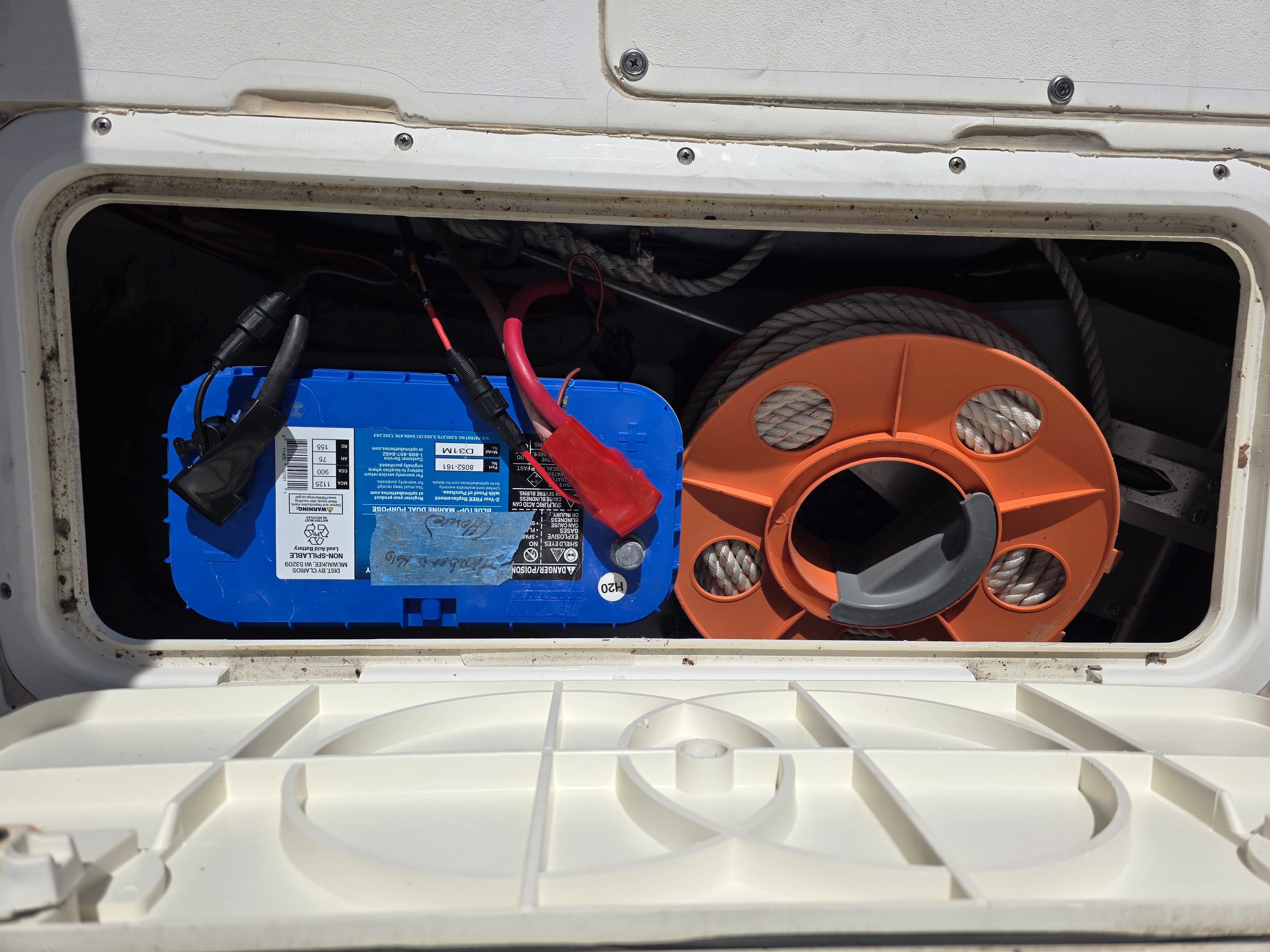 Battery and cable reel in a 1987 Mako 248 WAC boat compartment.