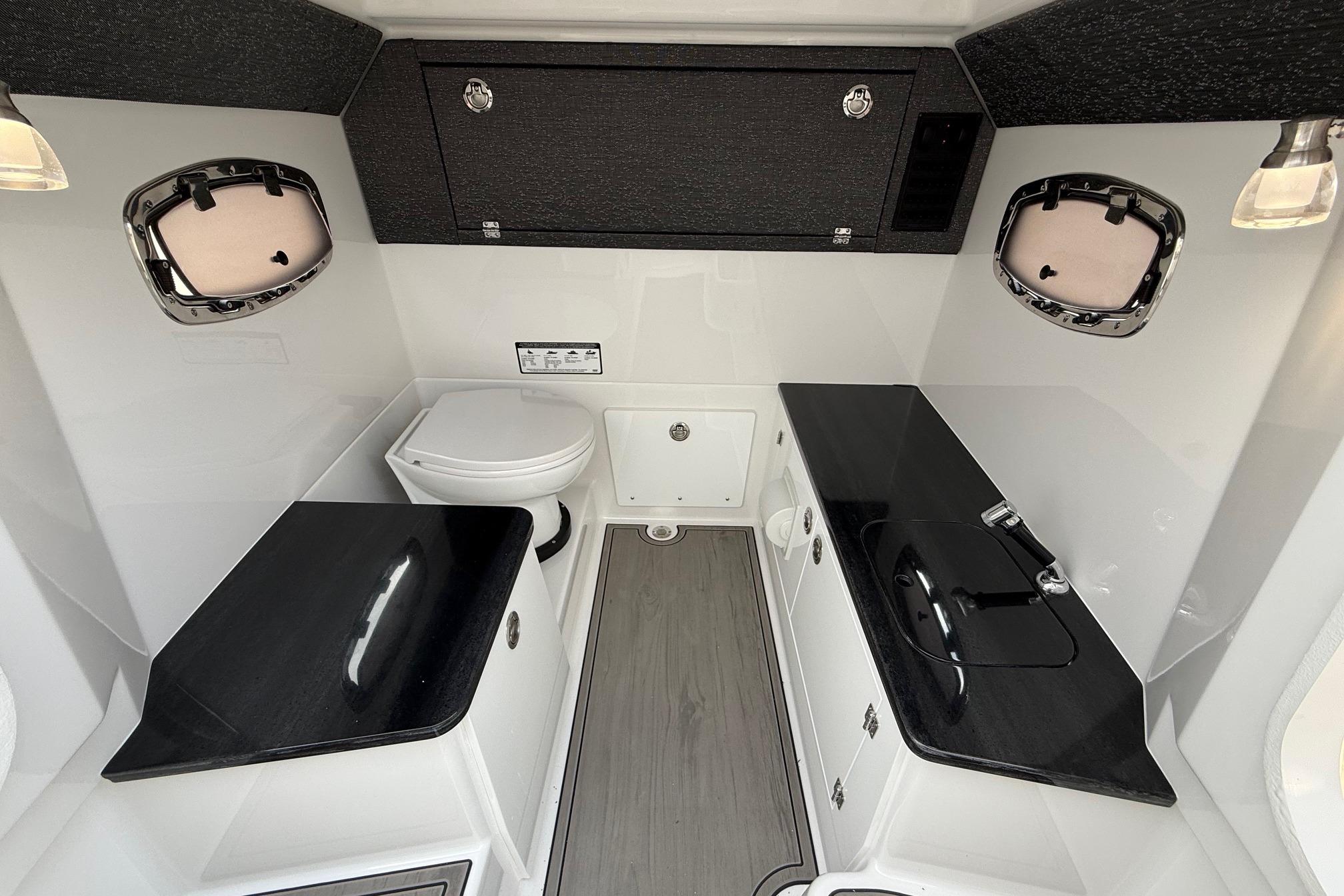 Luxurious bathroom interior of 2026 Monterey Elite 25 OB boat with sleek black countertops.