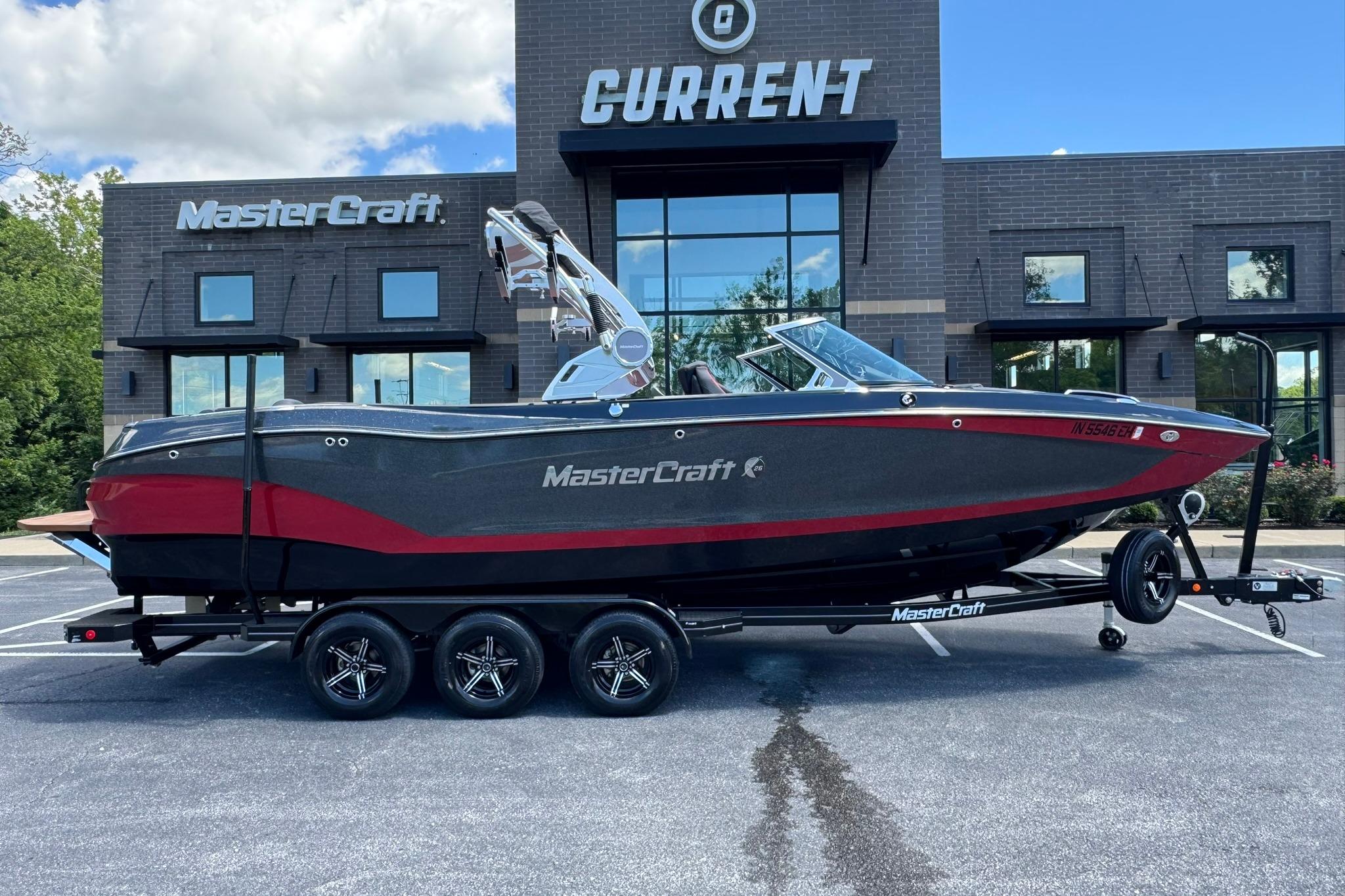2021 MasterCraft X26 boat on trailer, parked outside dealership, showcasing sleek design and modern features.