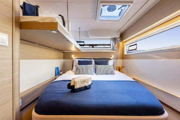 Luxurious cabin interior of 2025 Lagoon 43 yacht with modern bedding and skylight.