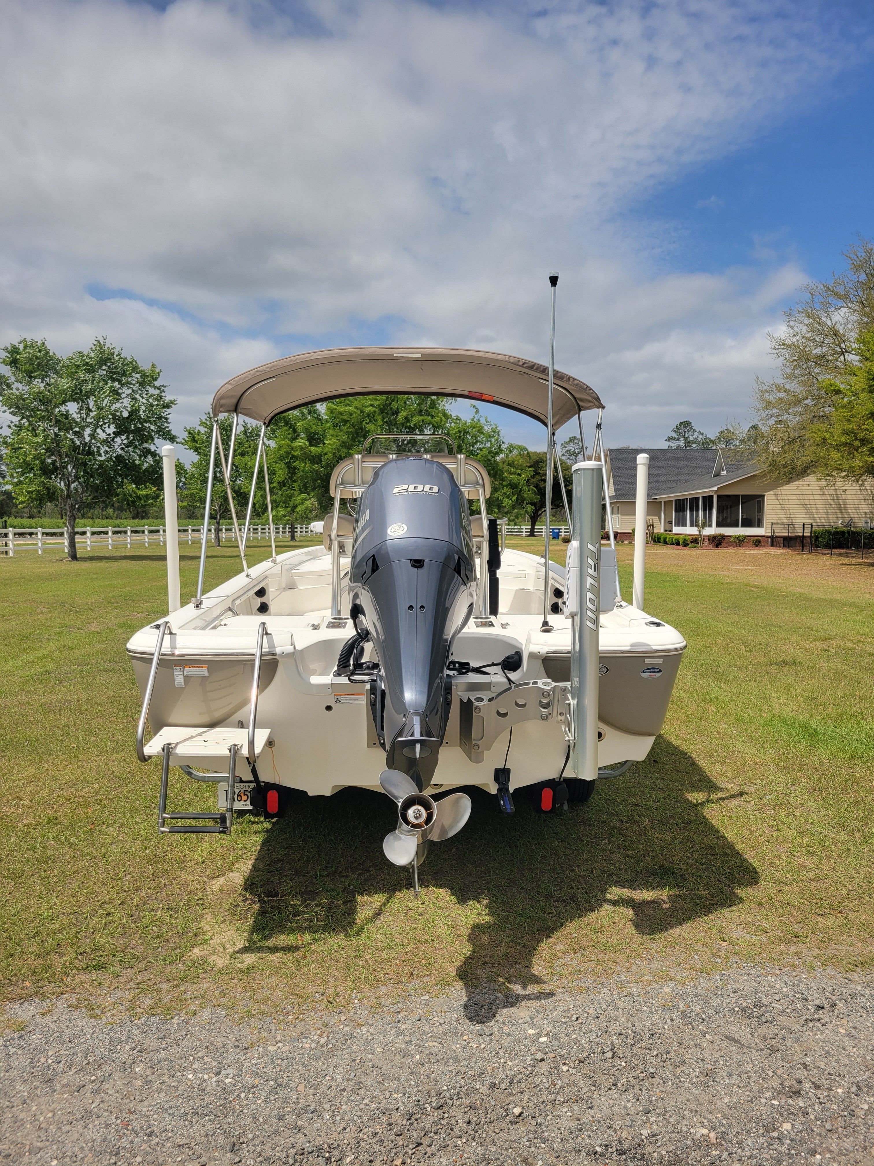 A NauticStar 2200 Sport boat is on grass with a house in the background.