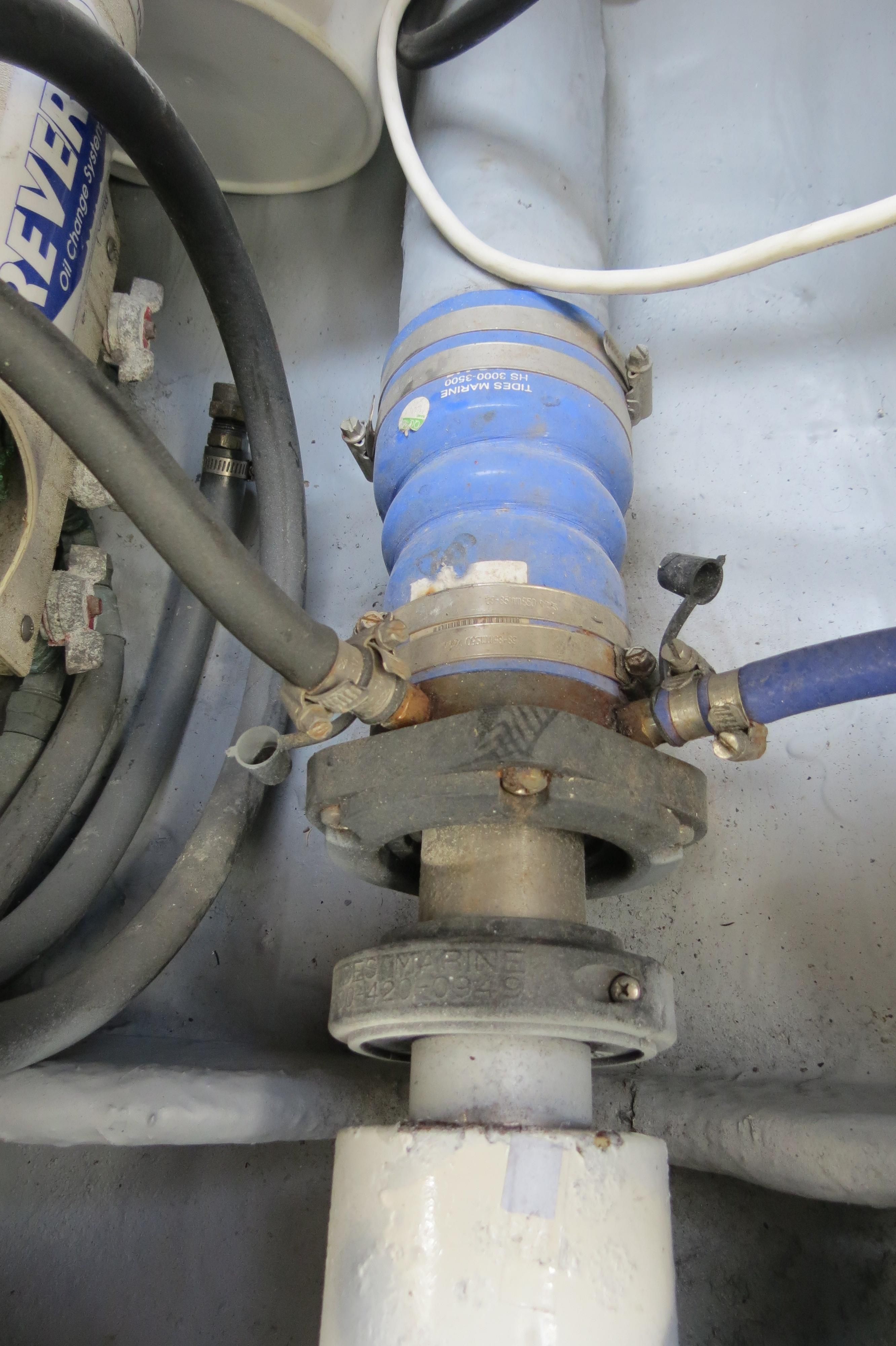 Close-up of a boat engine part with hoses and metal fittings.