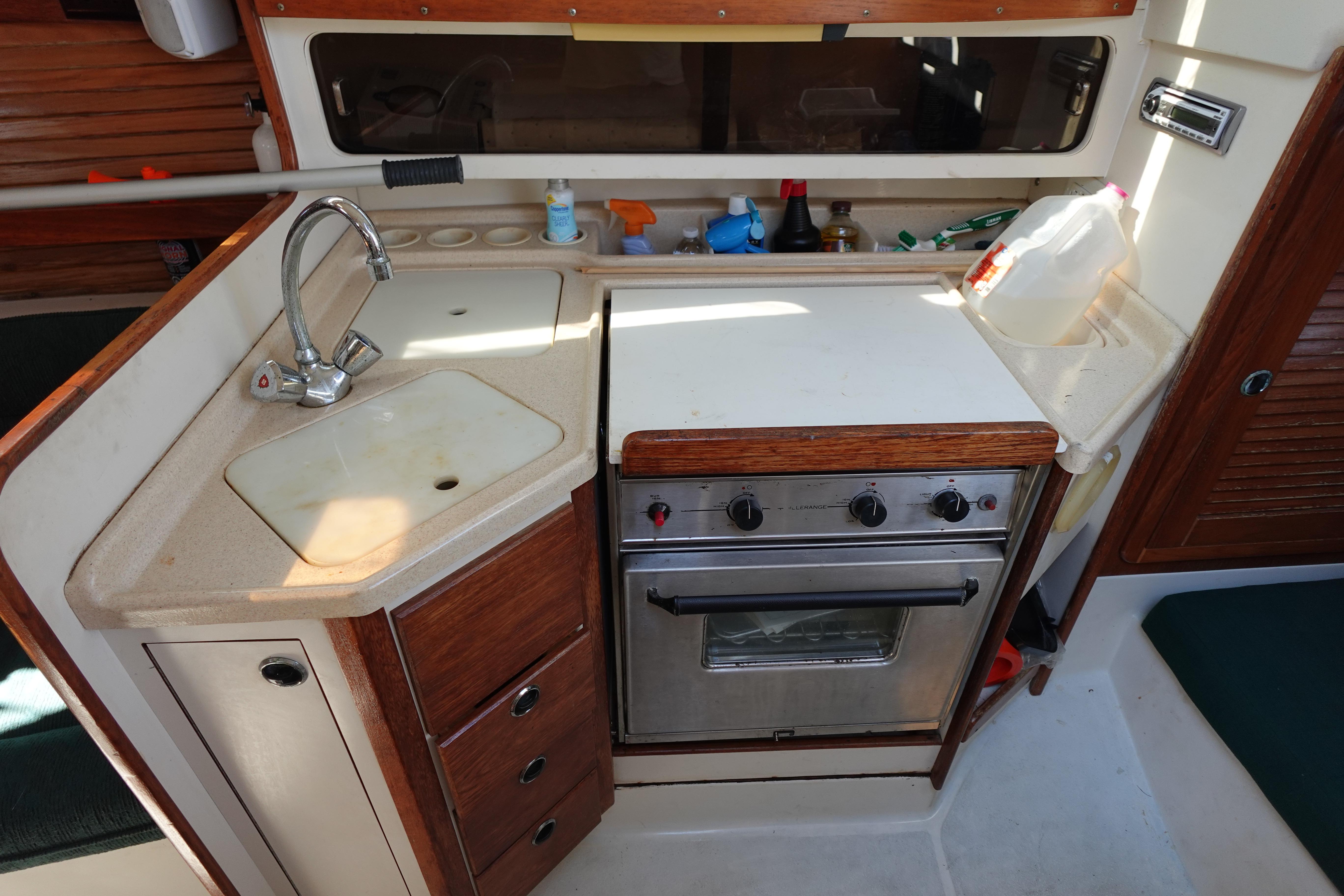 Compact kitchen in a 1997 Catalina 28 sailboat with sink and stove.