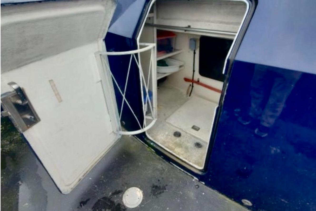 Open storage compartment on 1985 Hatteras 82 Convertible yacht, showcasing interior shelves and door.
